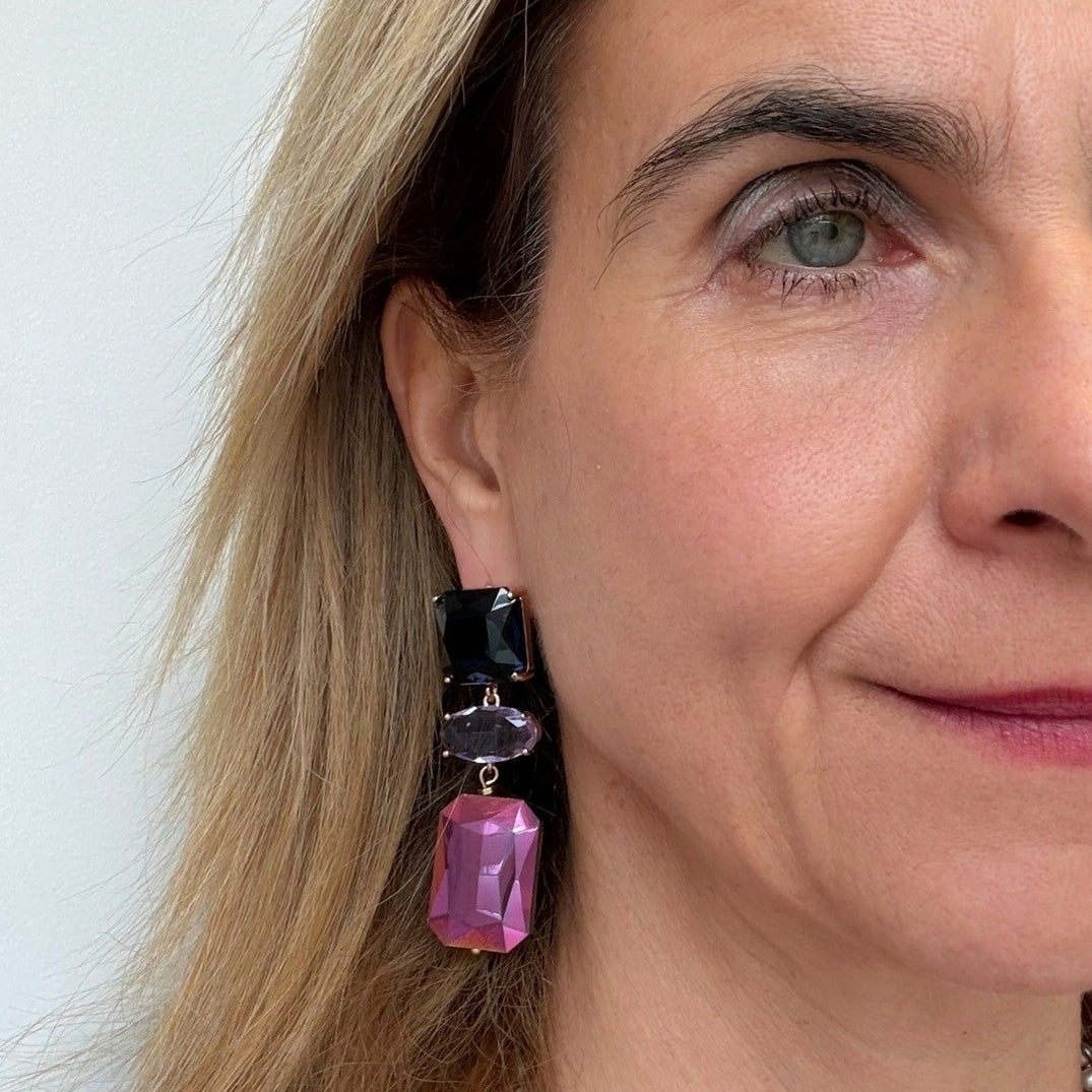 Close-up of a woman wearing pink and black earrings against a light background