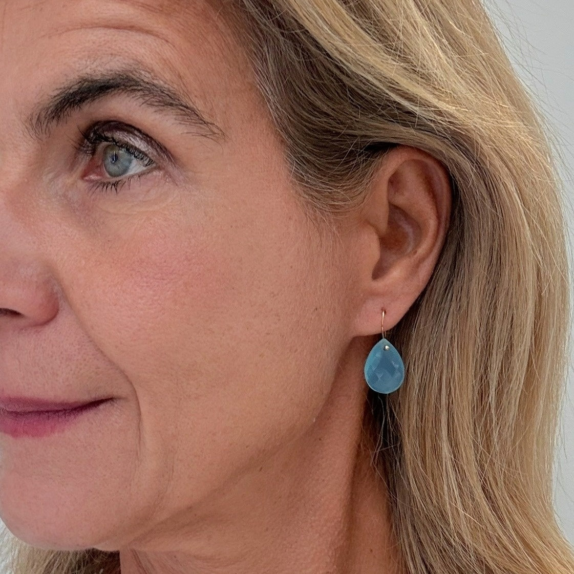 Close-up of a woman wearing a blue teardrop earring.