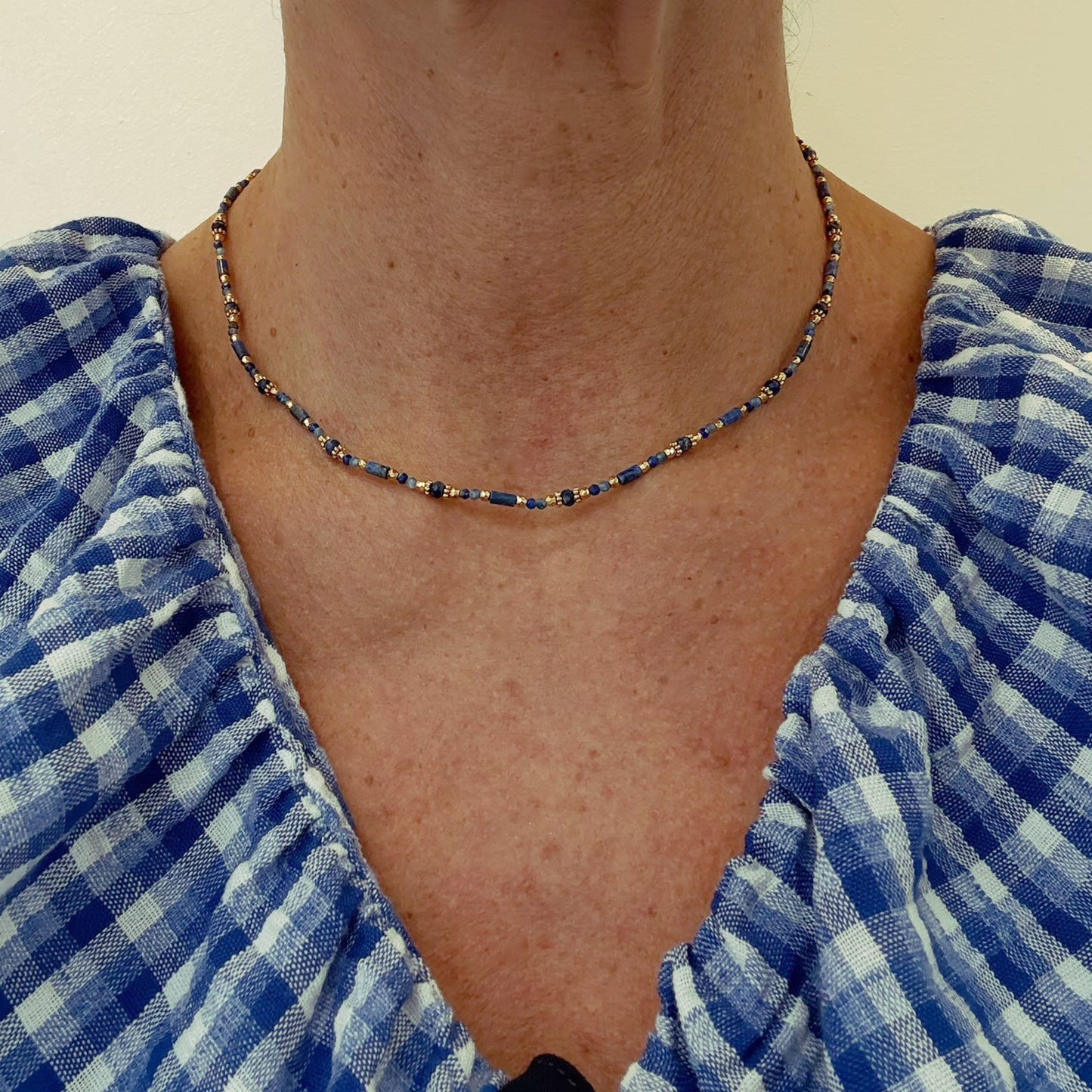 Necklace with small alternating different shaped dark blue and gold beads won on model