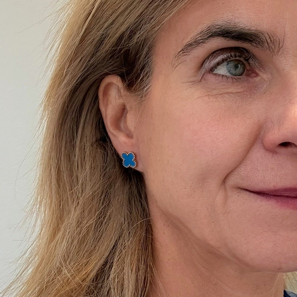 Close-up of a woman wearing blue earrings with a neutral background