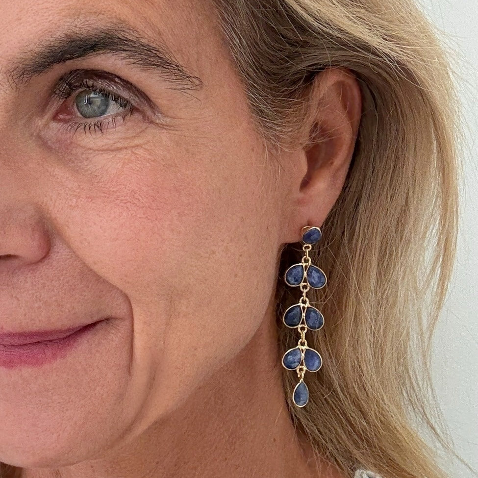 woman wearring gold earrings with 8 small teardrop shaped Lapis Lazuli gemstone charms