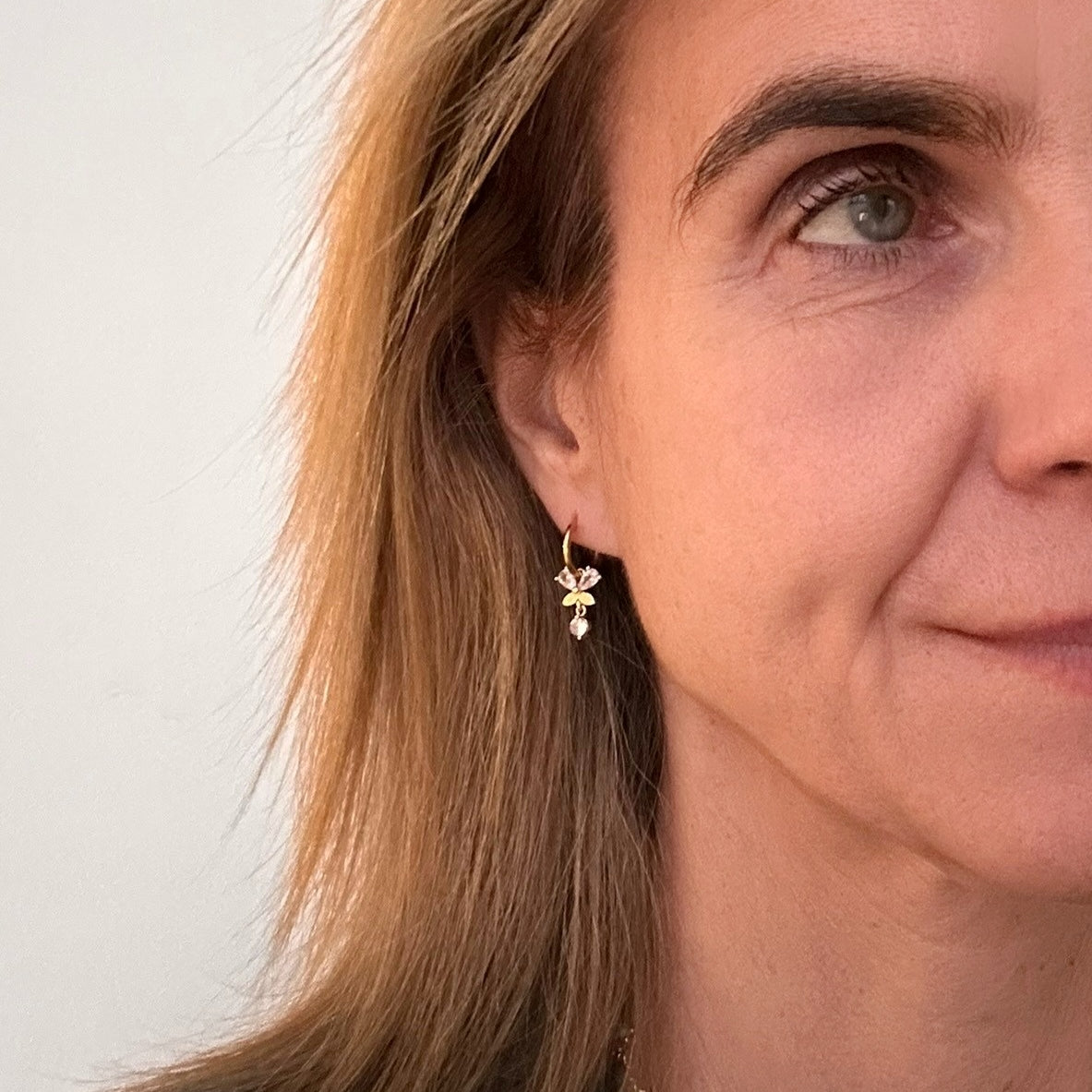 te gold hoop earrings with sparkly butterfly and small dangling diamond charms worn on model