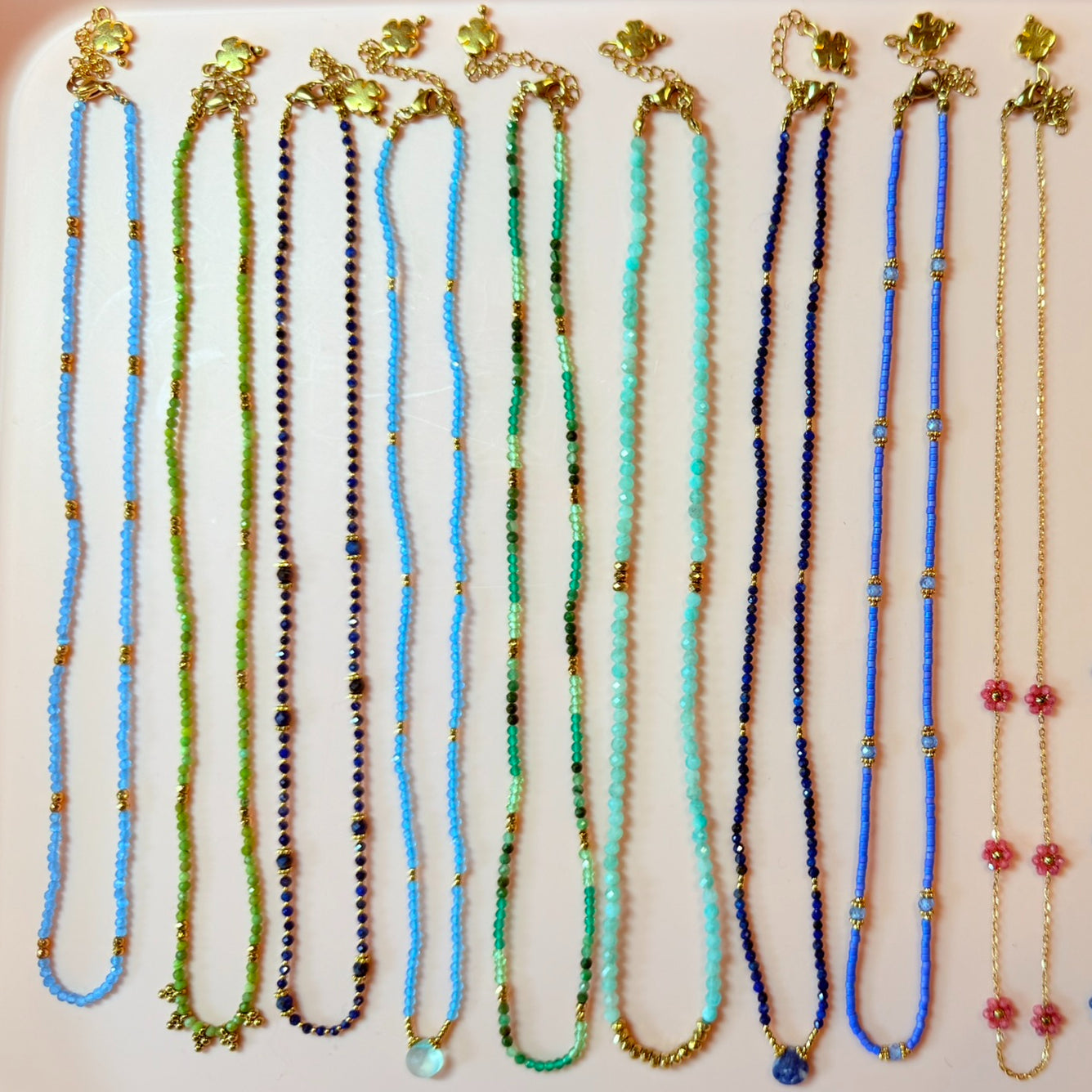 Set of multicoloured beaded necklaces with gold clasps on a white background