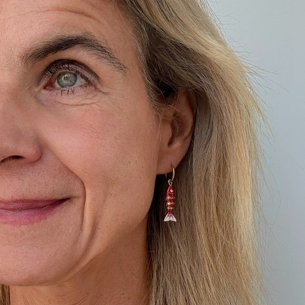 woman wearring gold hoop earrings with red moving fish charms