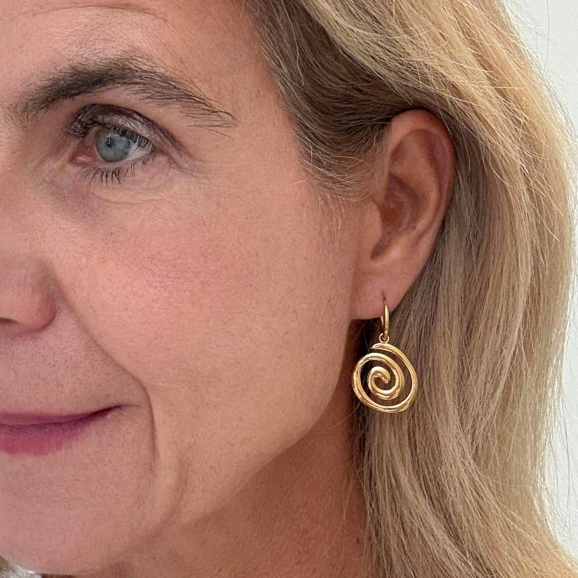 Gold hoop earrings with gold swirl charms on model