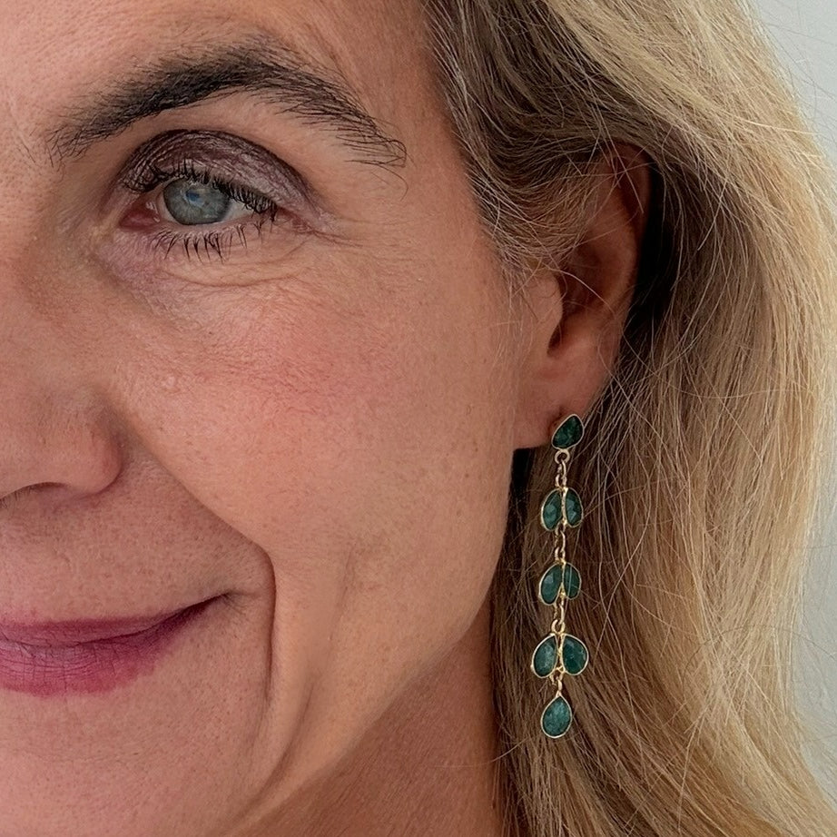 Woman wearring gold earrings with 8 small teardrop shaped Green Onyx gemstone charms