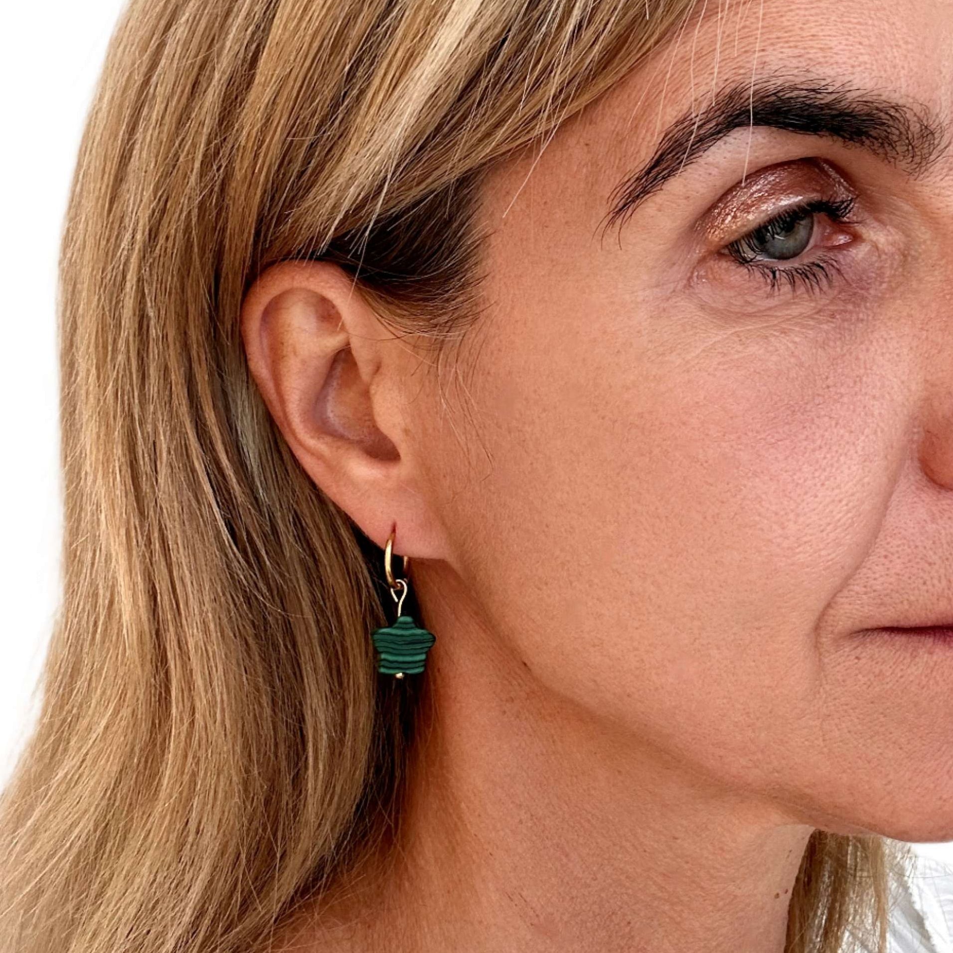 gold hoop with green star charm worn on woman