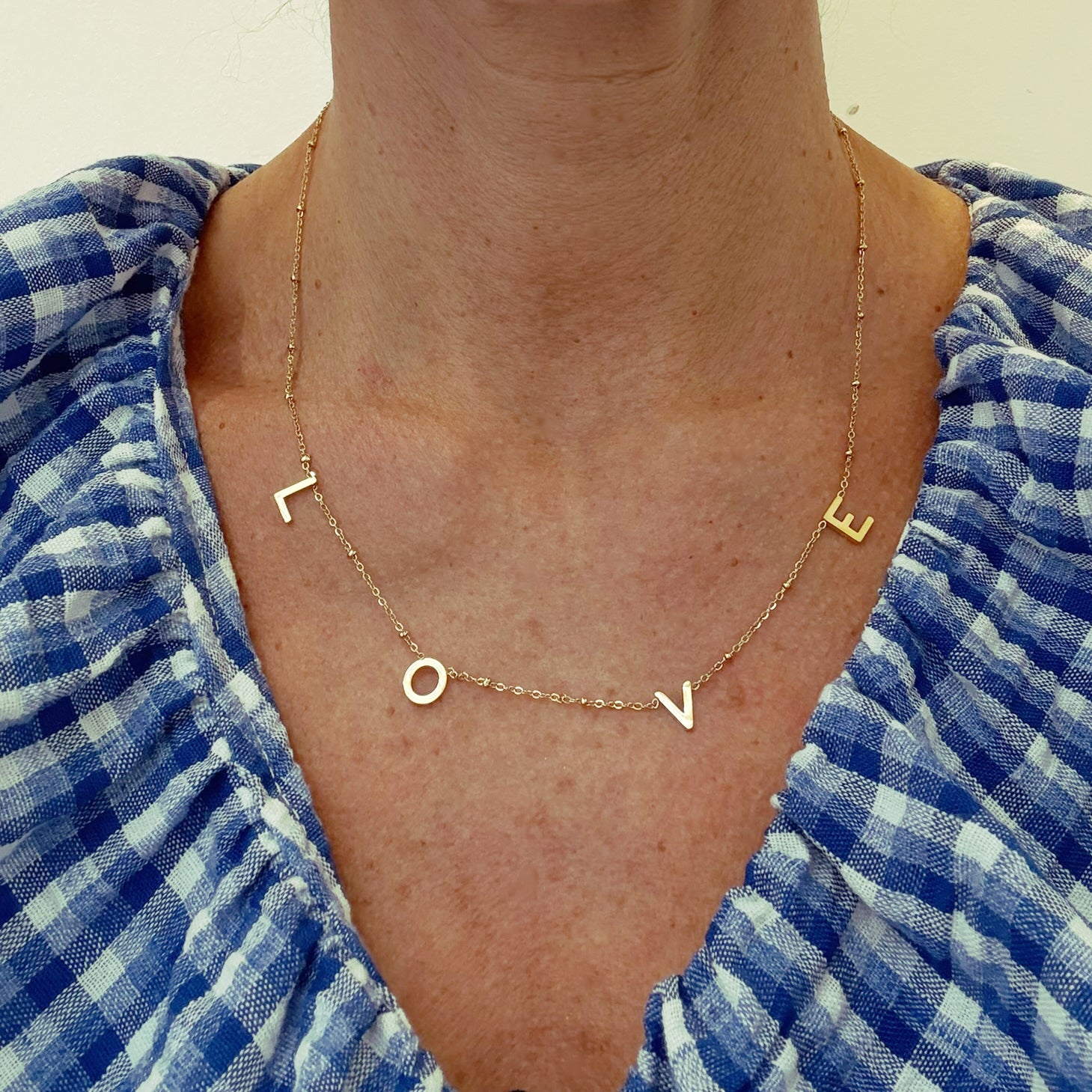 Delicate gold chain necklacewith the letters LOVE worn on model