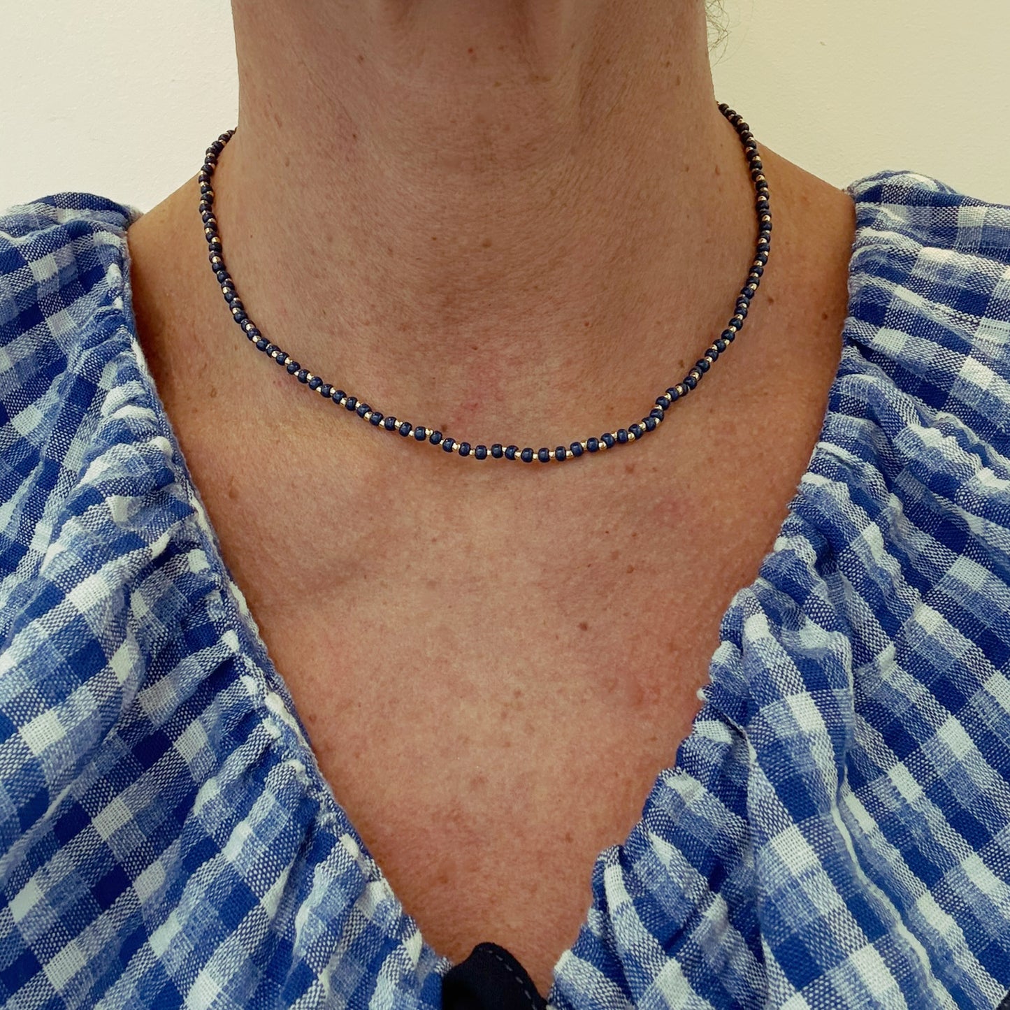 Necklace with round blue and gold beads worn on model