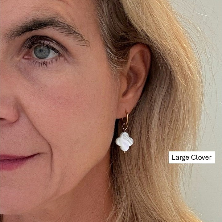 Close-up of a woman wearing a large clover-shaped earring in Mother of pearl