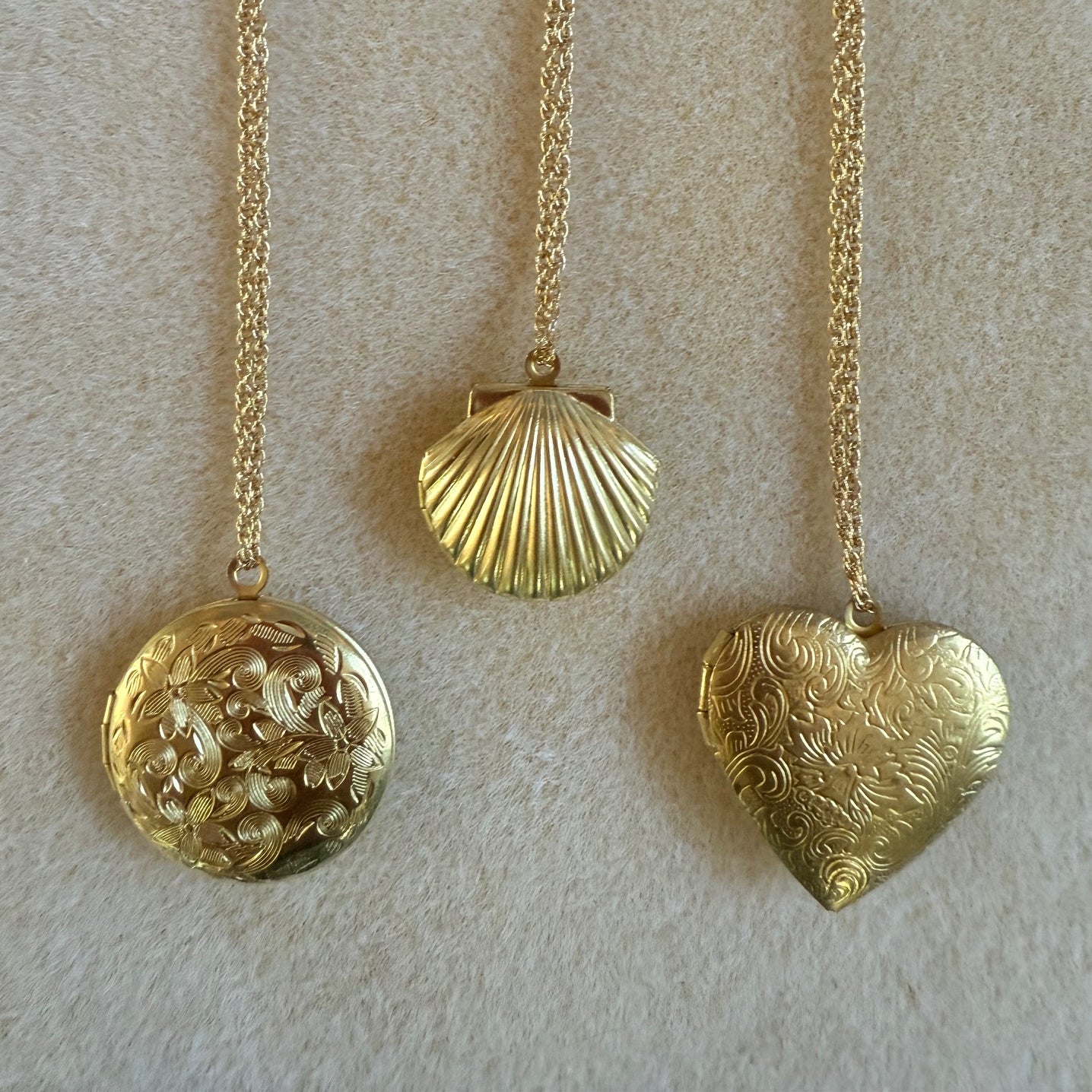 Three gold lockets on belcher twisted chains - a heart, a clam , and a round shape with floral pattern
