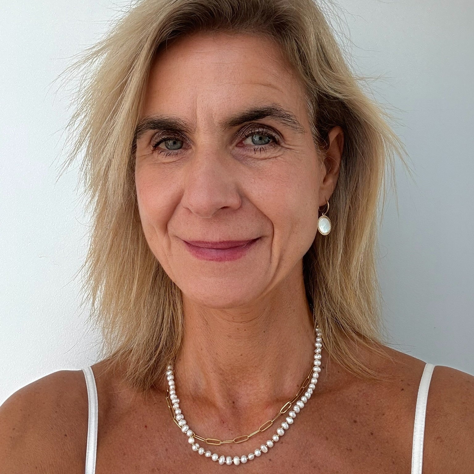 woman wearring large round mother of pearl charm hoops and necklace with freshwater pearls