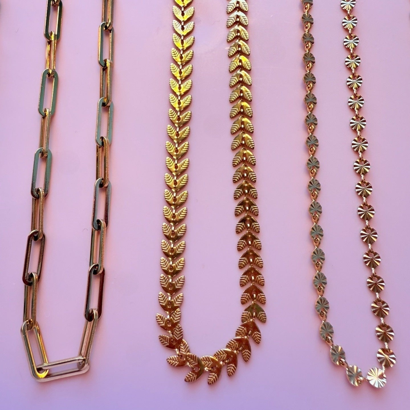 Three gold necklaces with paperclip chain, fishtail chain and round disc chain