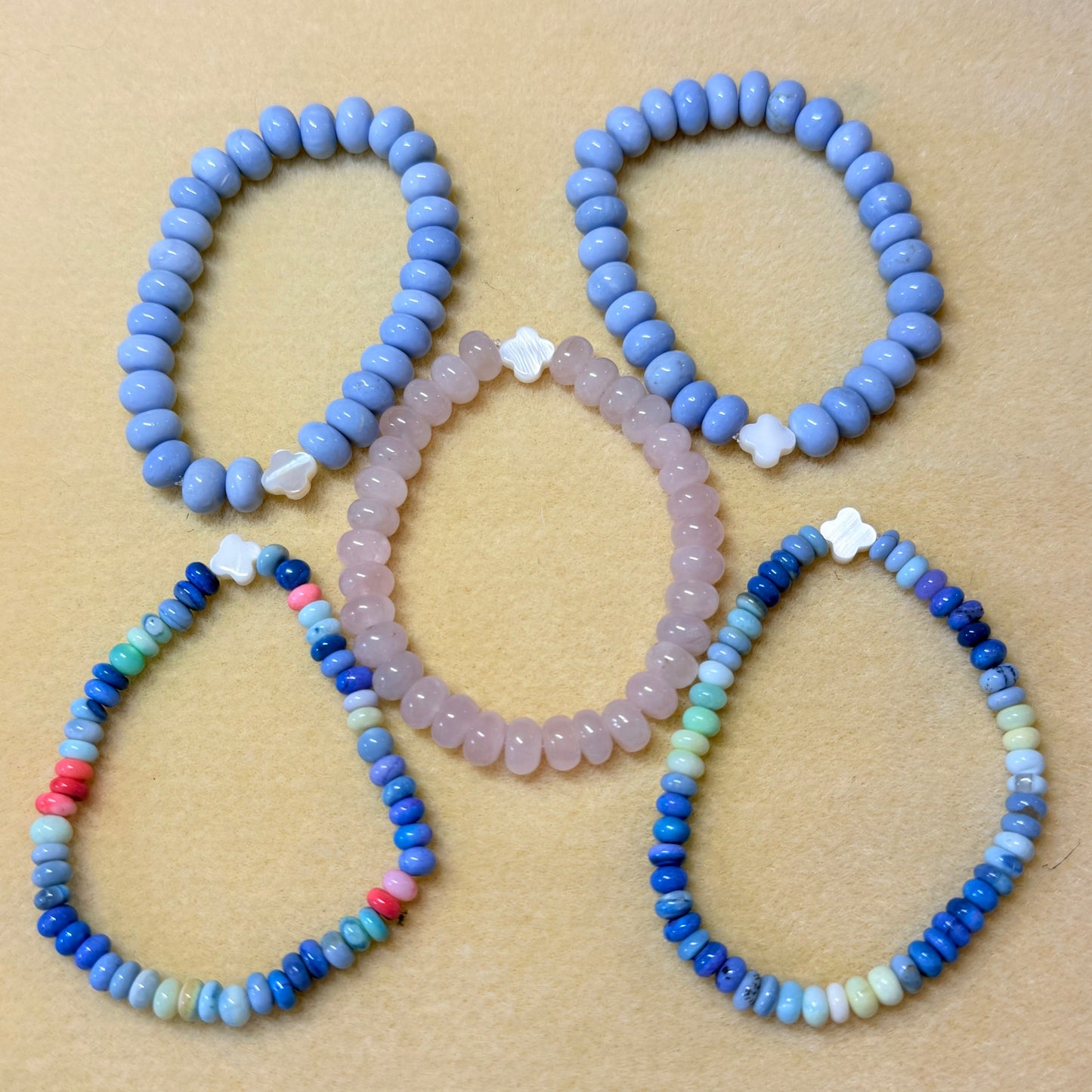 Set of beaded opal rondelle bracelets on a beige background