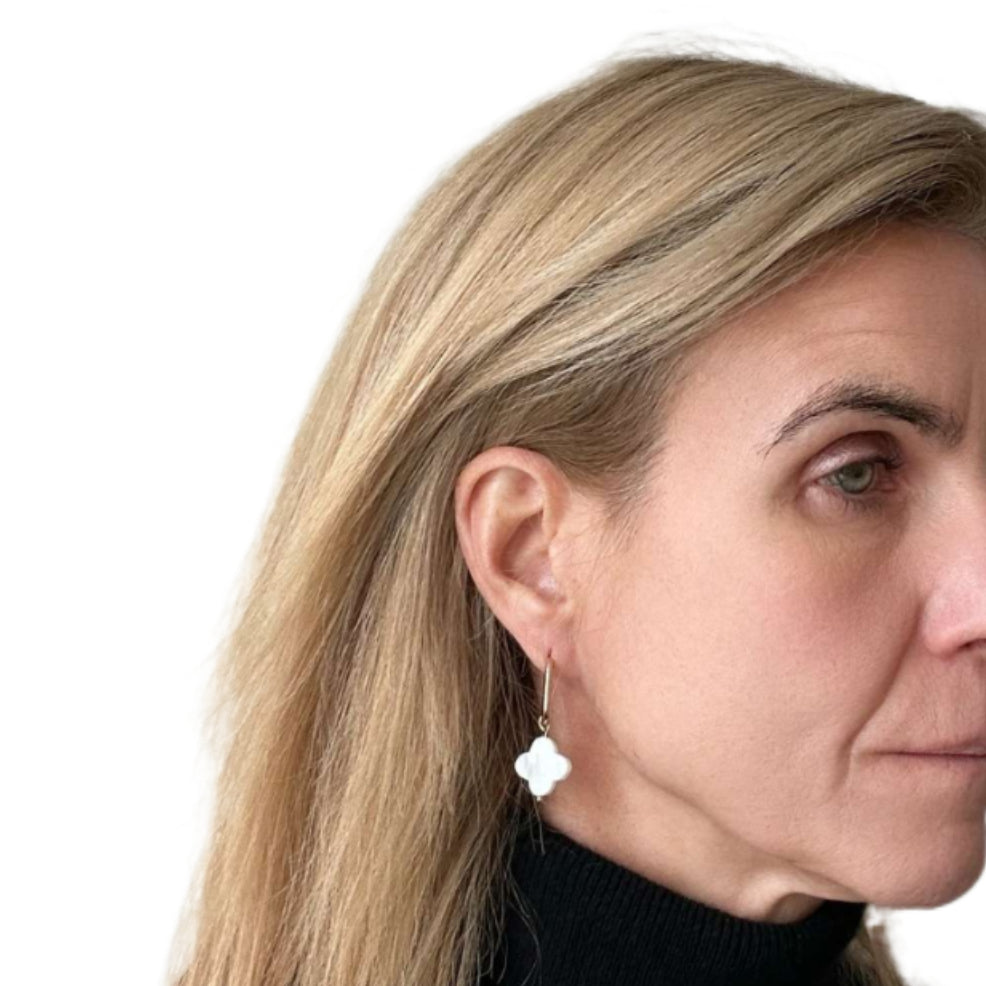 Close-up of a woman wearing a mother of pearl clover shaped hoop earring