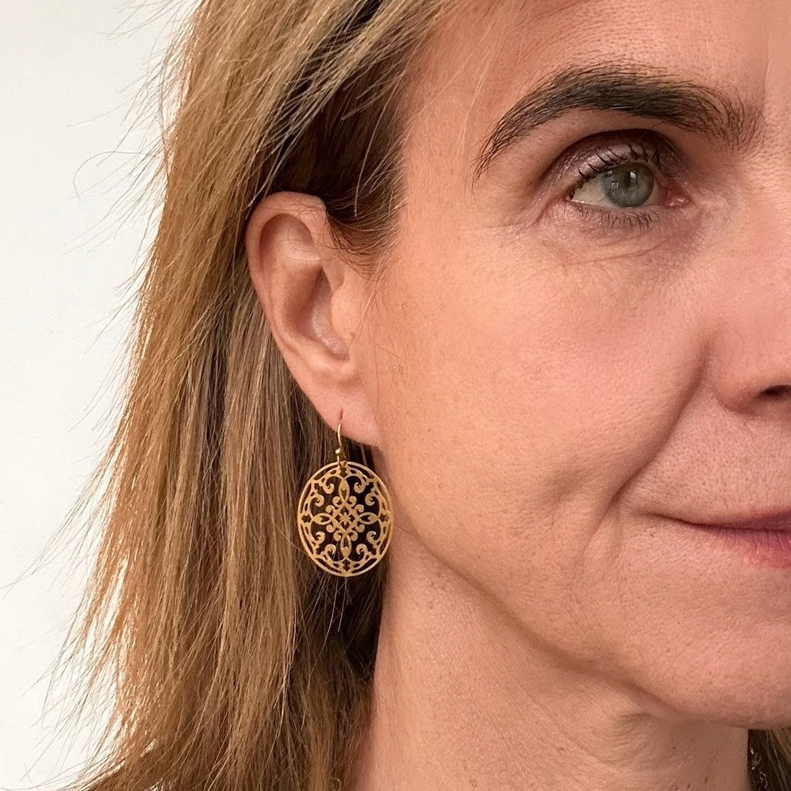 Small bohemian patterned gold round earrings on model