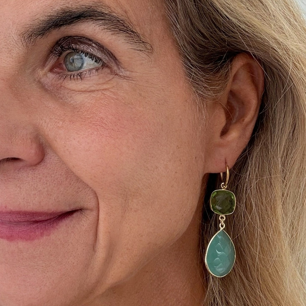 Close-up of a woman wearing gold and green earrings.