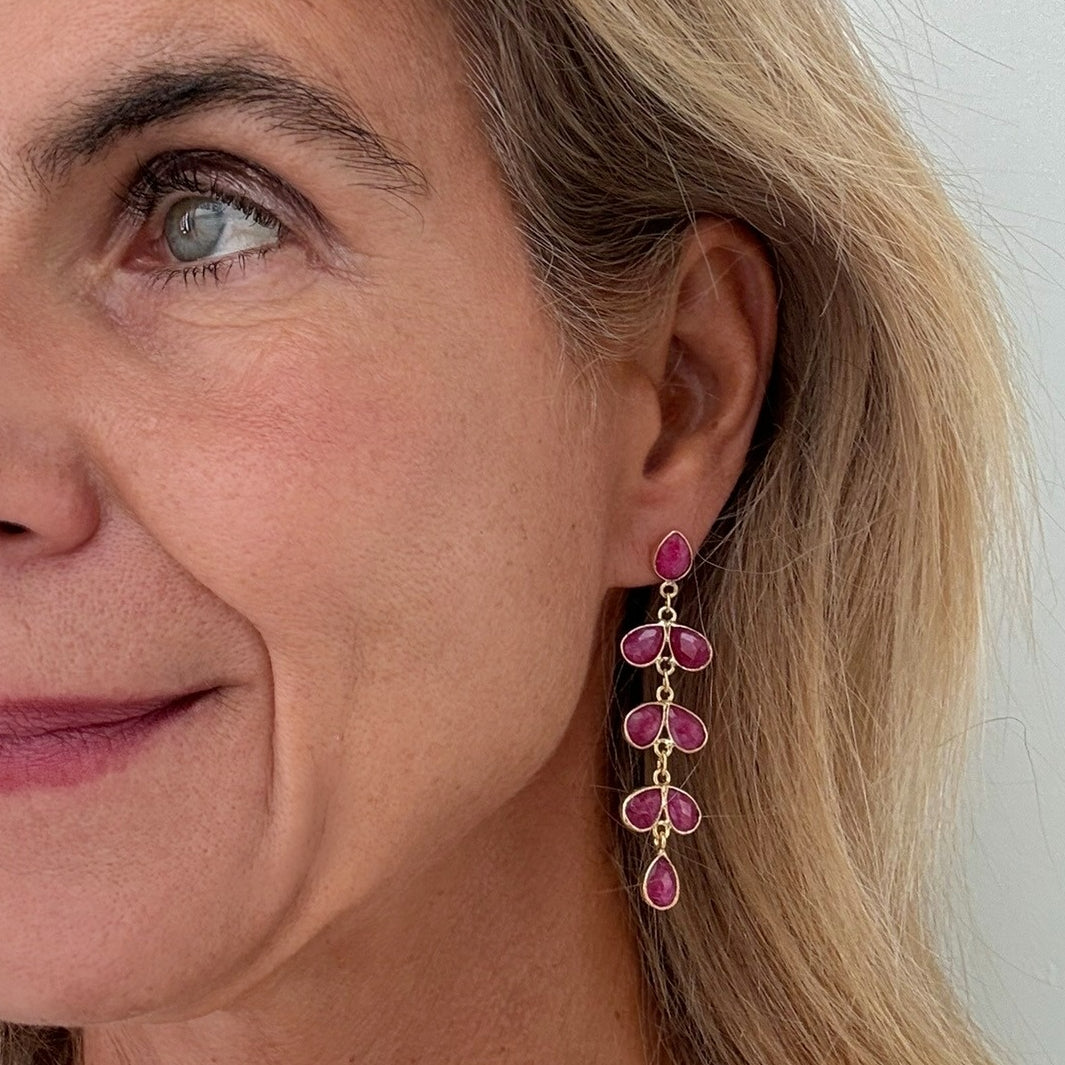 woman wearring Lovely gold earrings with 8 small teardrop shaped pink quartz gemstone charms