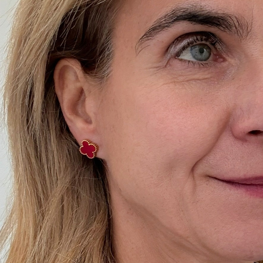 Close-up of a woman wearing red earrings with gold accents.