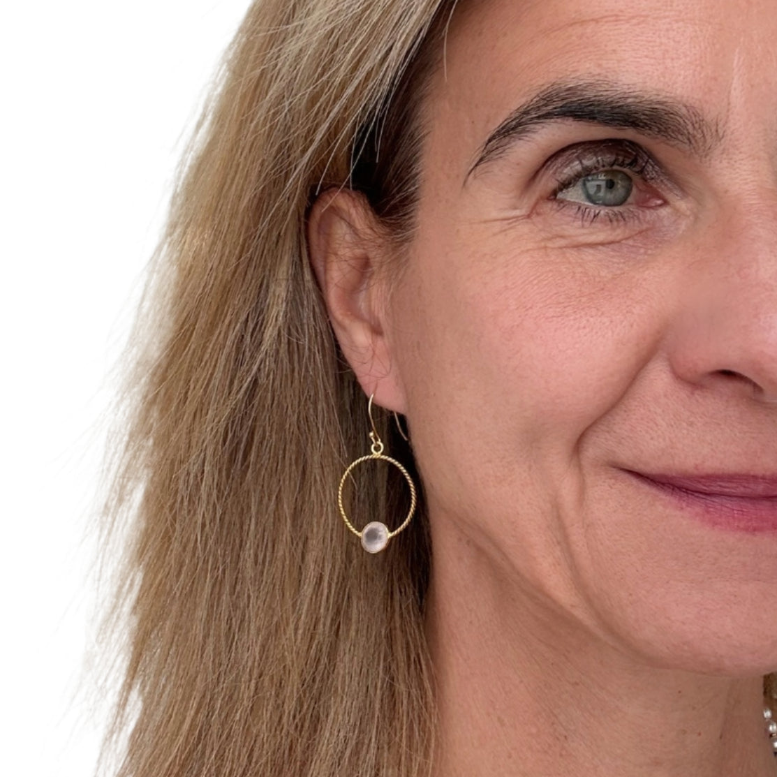 Lovely twisted gold circle earrings with small Rose Quartz charm worn on model