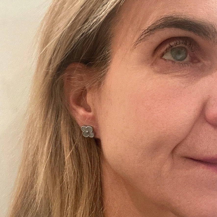 stud earrings are made of silver stainless steel in a clover shape. on model