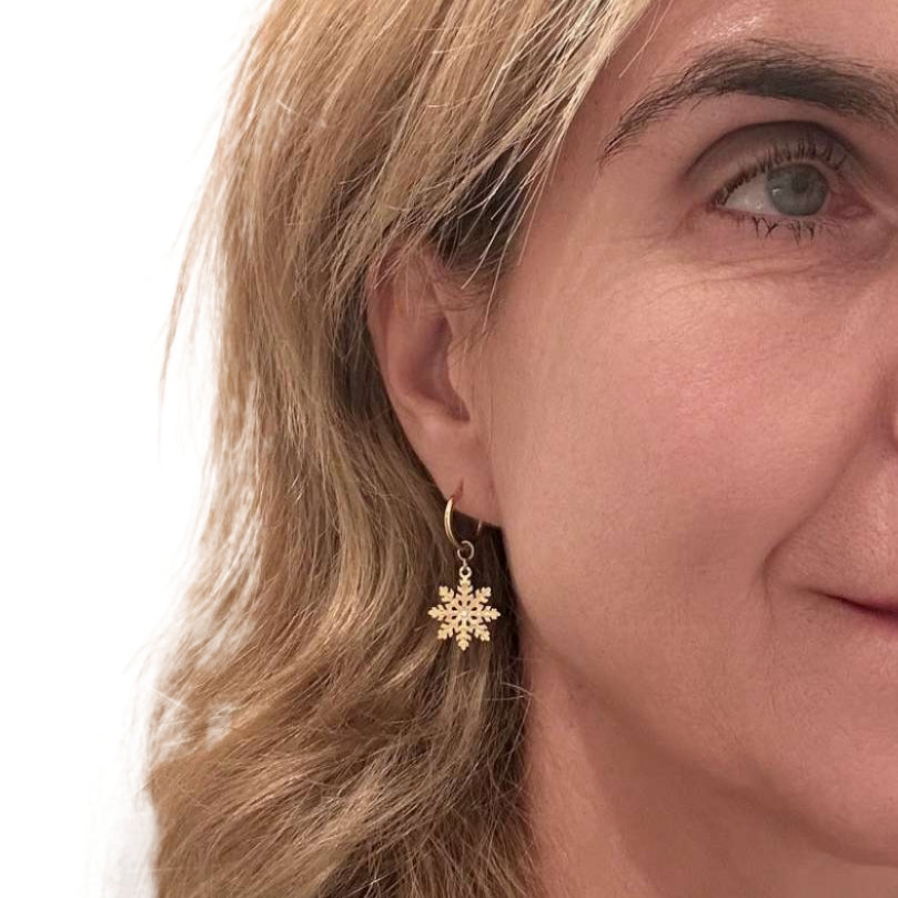 gold snowflake hoop earrings worn on woman