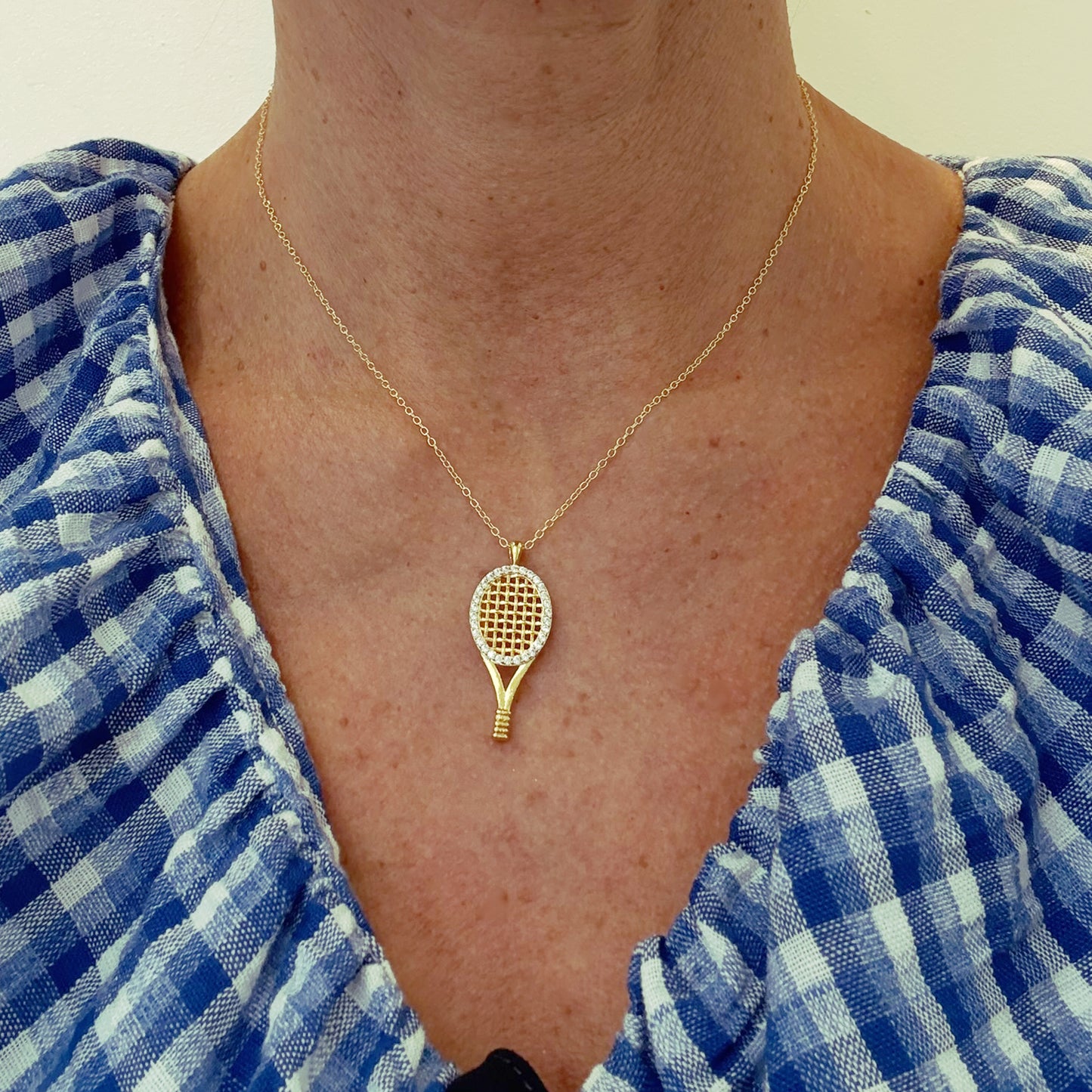 Delicate gold belcher chain necklace with fun sparkly tennis racket charm worn on model