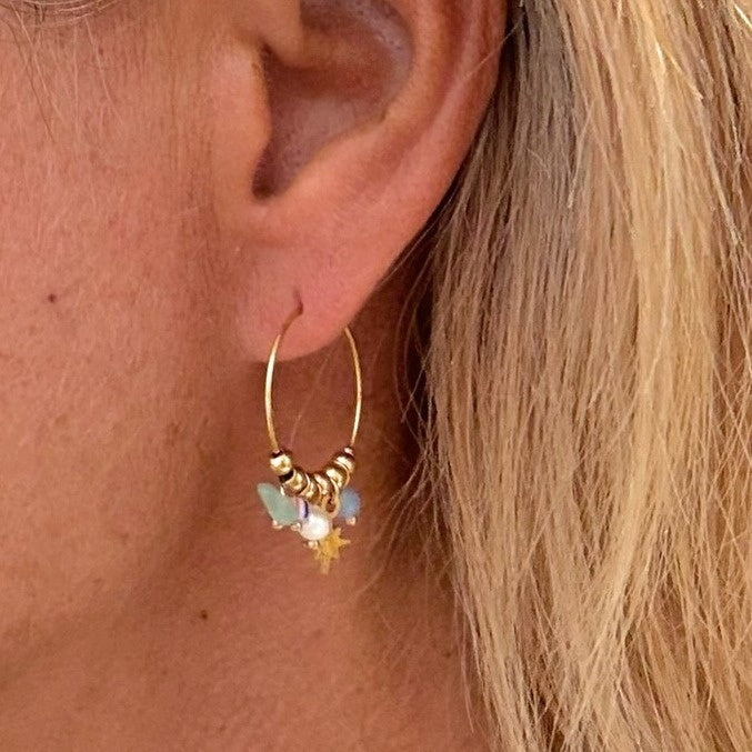 Medium thin hoops with dangling blue and gold beads on the ear