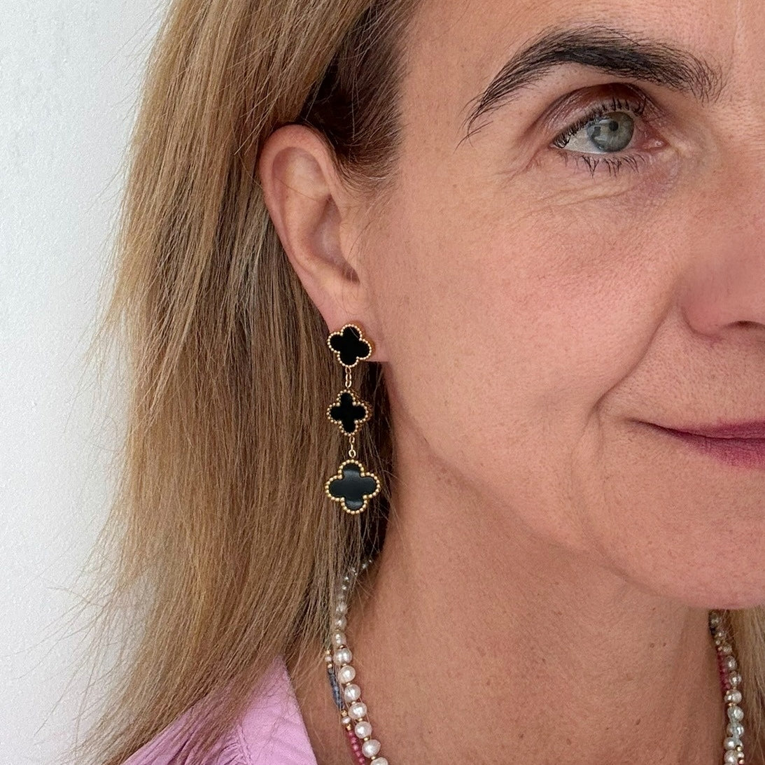 Clover shaped stud earrings with two dangling clover shaped charms all in black worn on model