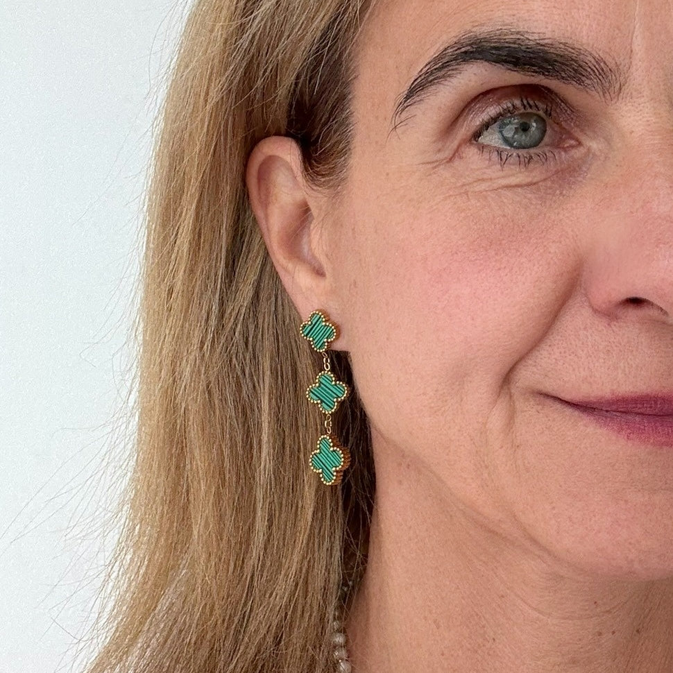 Clover shaped stud earrings with two dangling clover shaped charms all in malachite style green worn on model