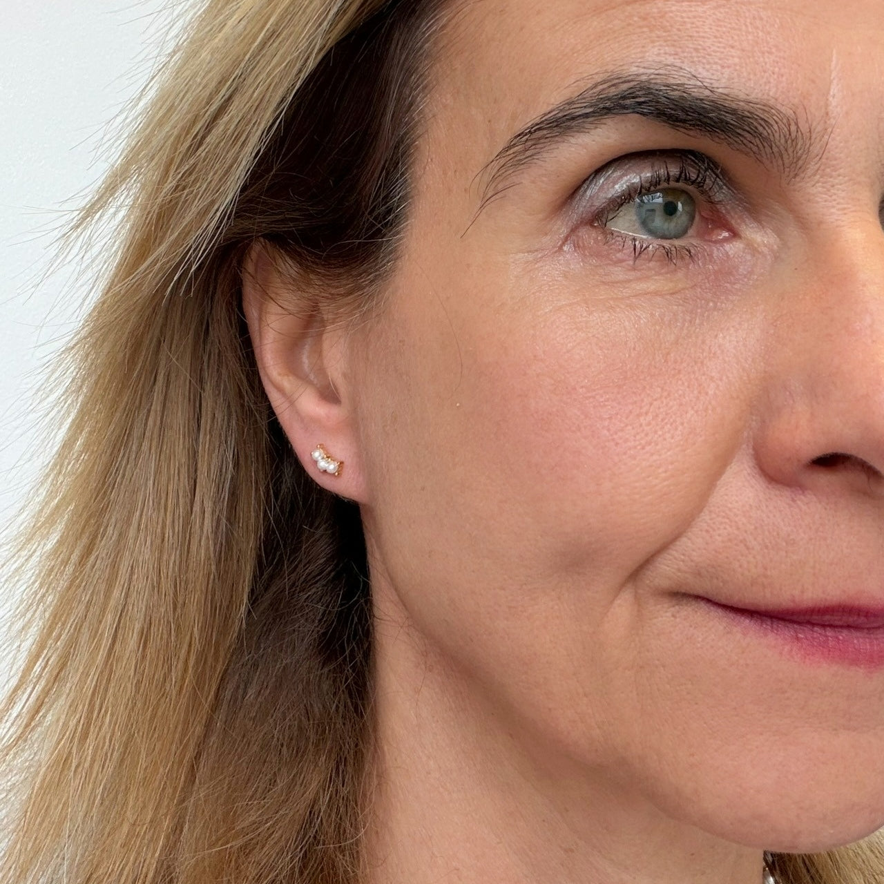 Woman wearring stud earrings with three pearls.