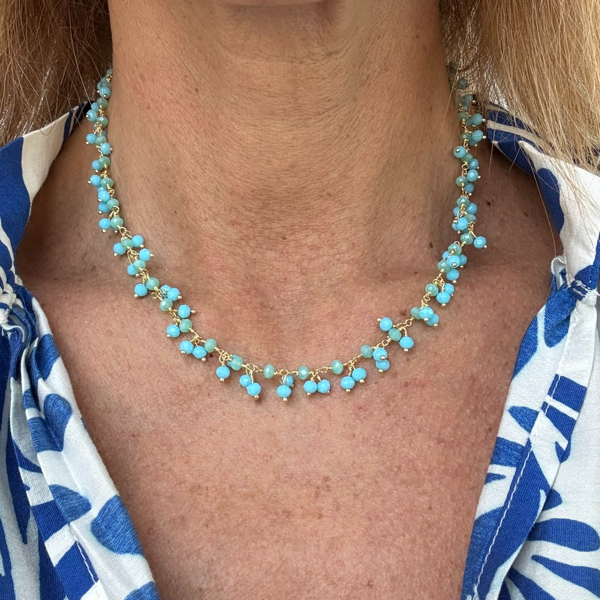 Gold necklace with bright blue Aquamarine and green Prehnite gemstone beads arranged in clusters worn on model