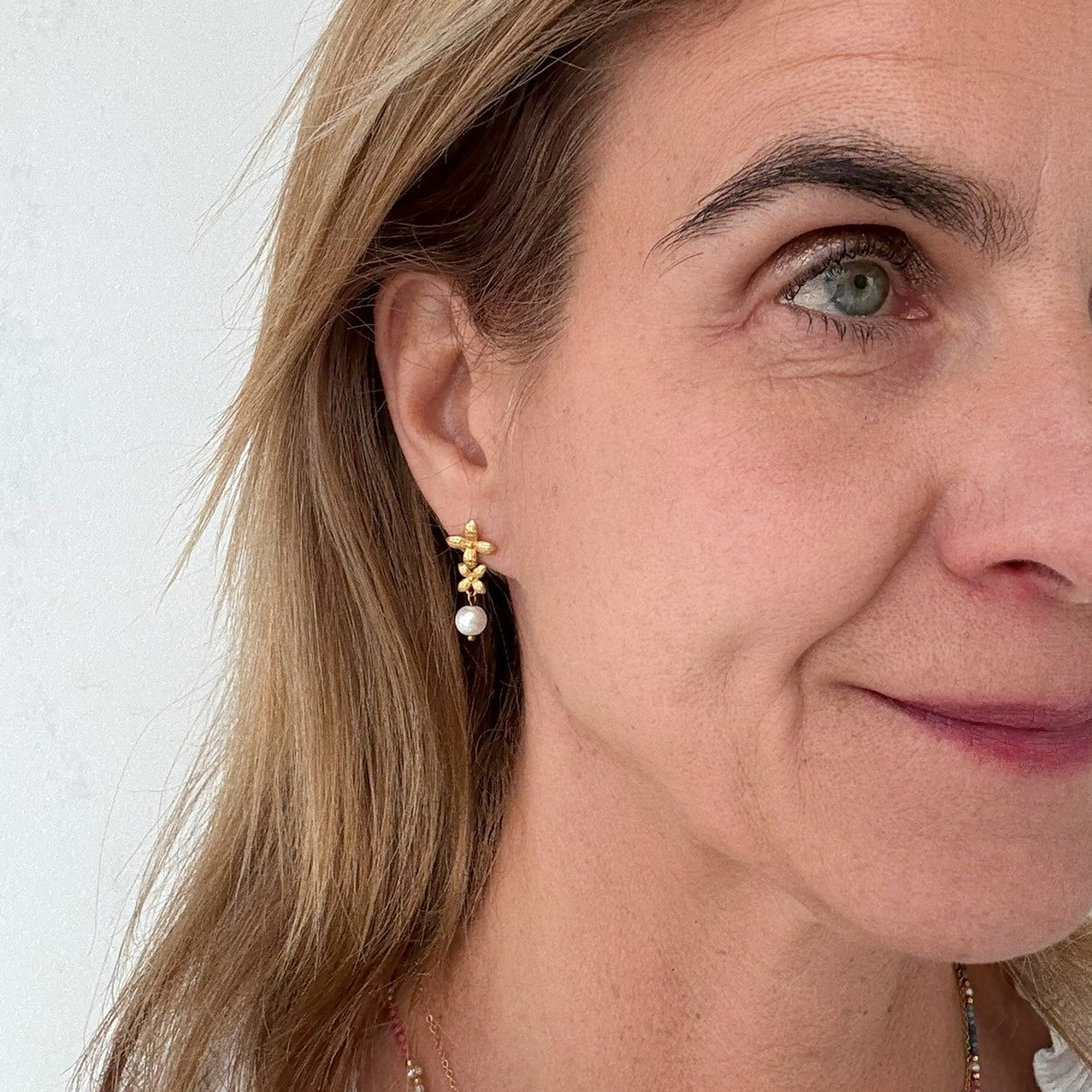 These lovely delicate earrings include two flowers and a dangling freshwater pearl worn on model