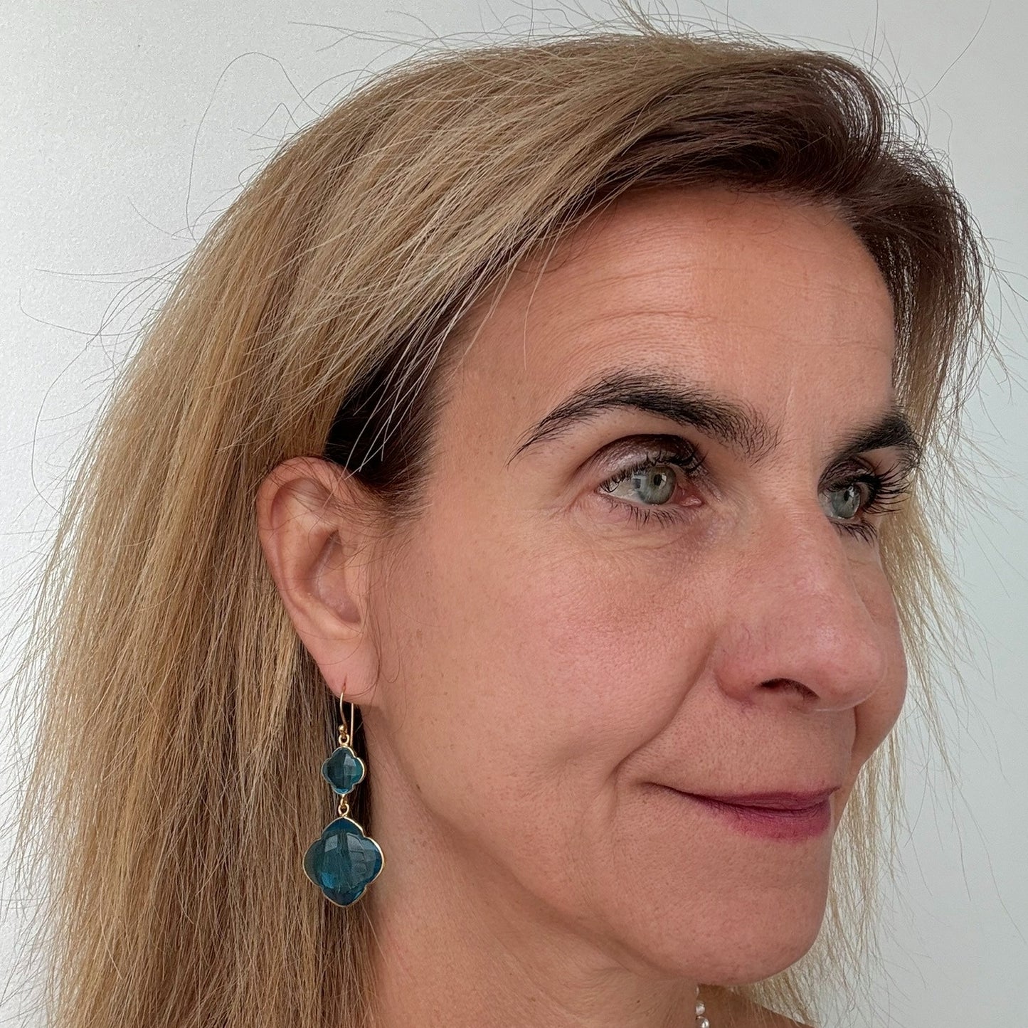 Big dangling earrings with two Sky Blue gemstone clover shaped charms worn on model