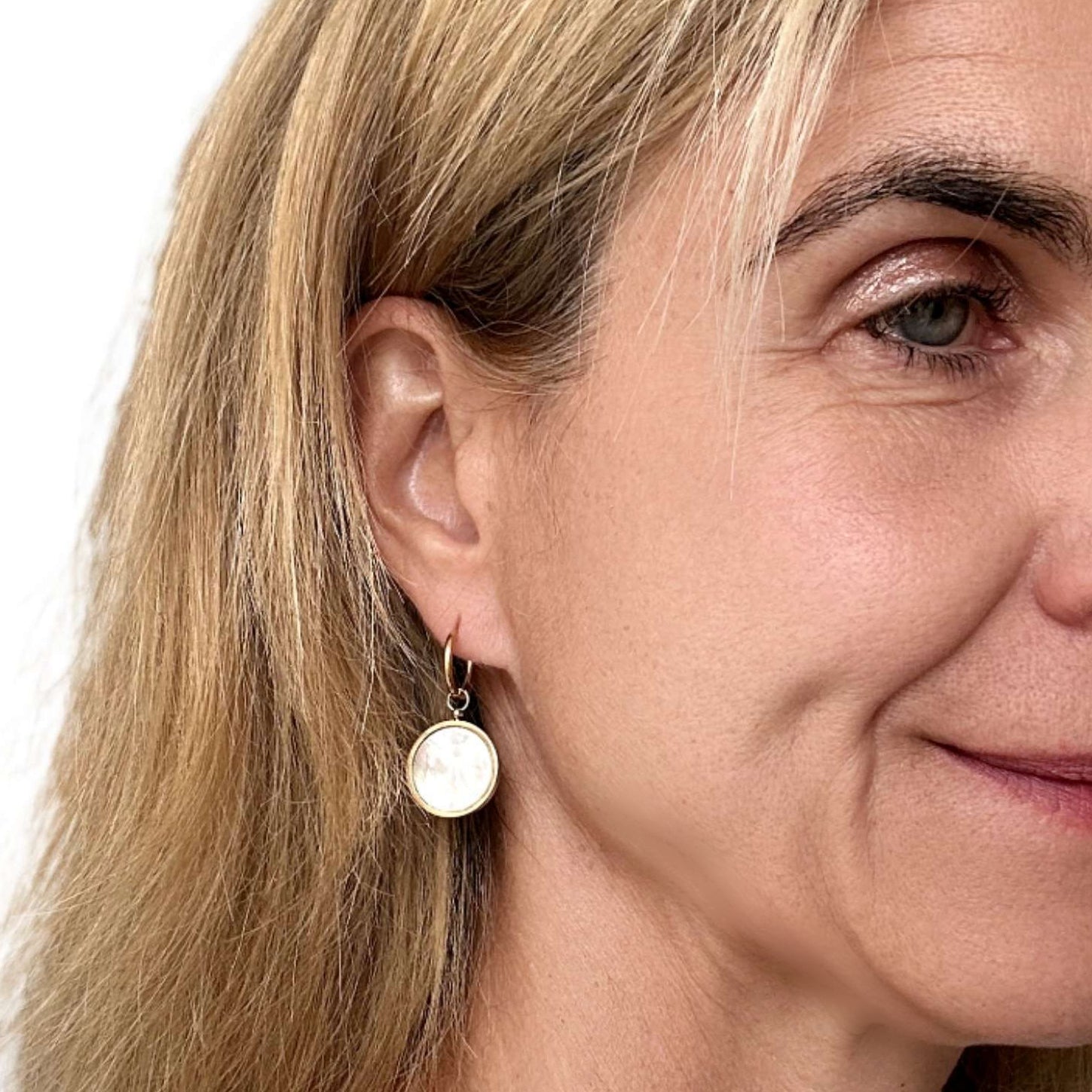 woman wearring gold hoops with mother of pearl large round charms