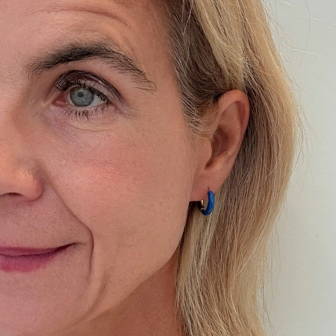 Huggie hoop earrings with royal blue enamel worn on woman