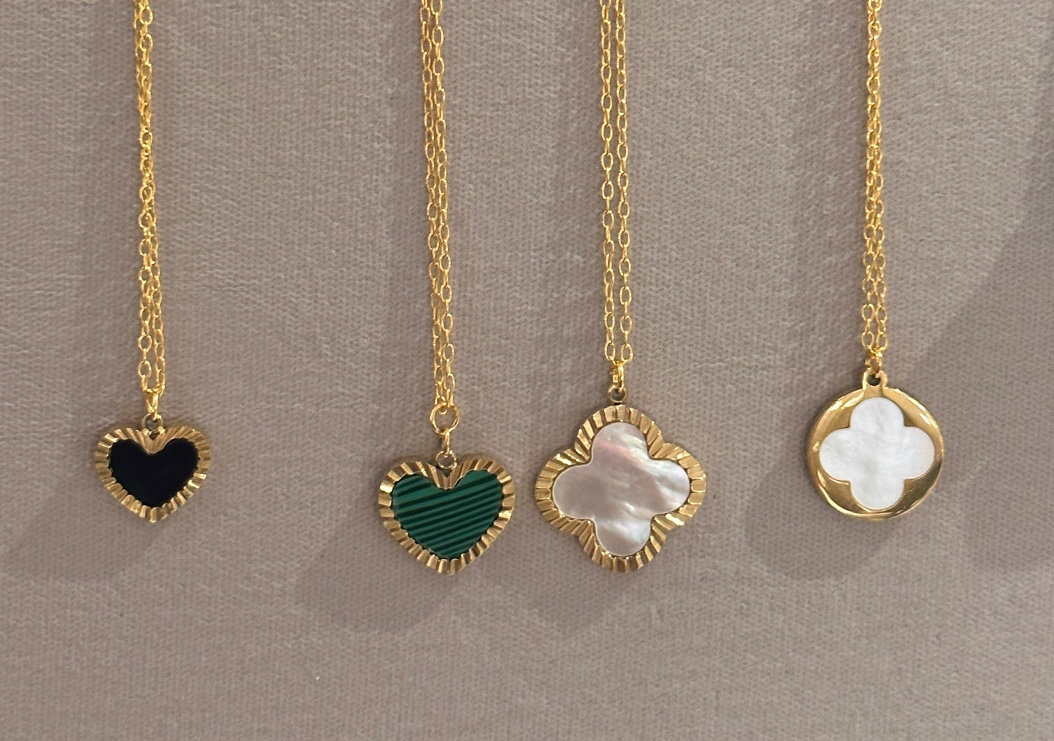 necklaces with charm pendants in gold, mother of pearl, black and green heart/clover shapes