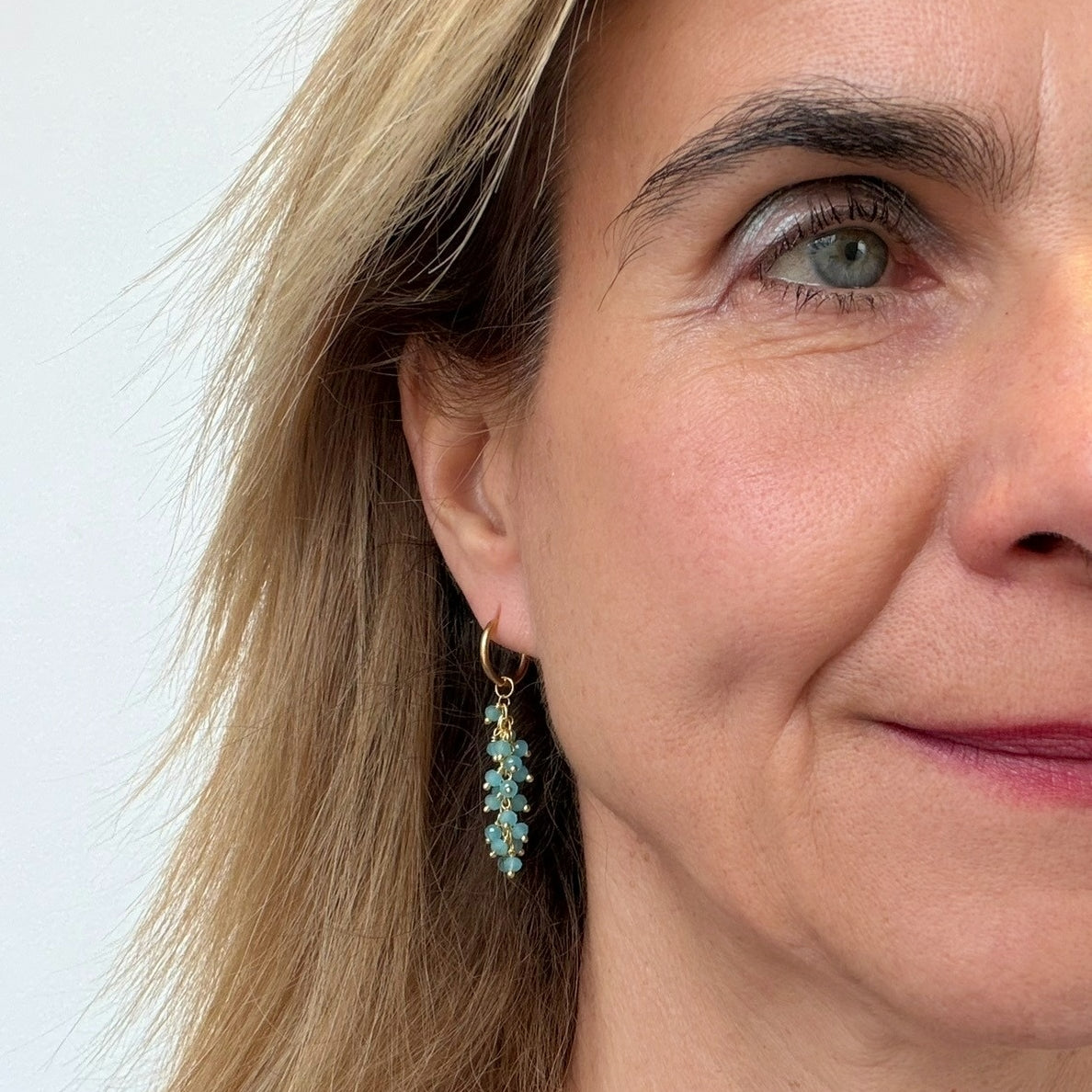 Close-up of a woman wearing a pair of earrings with a light background