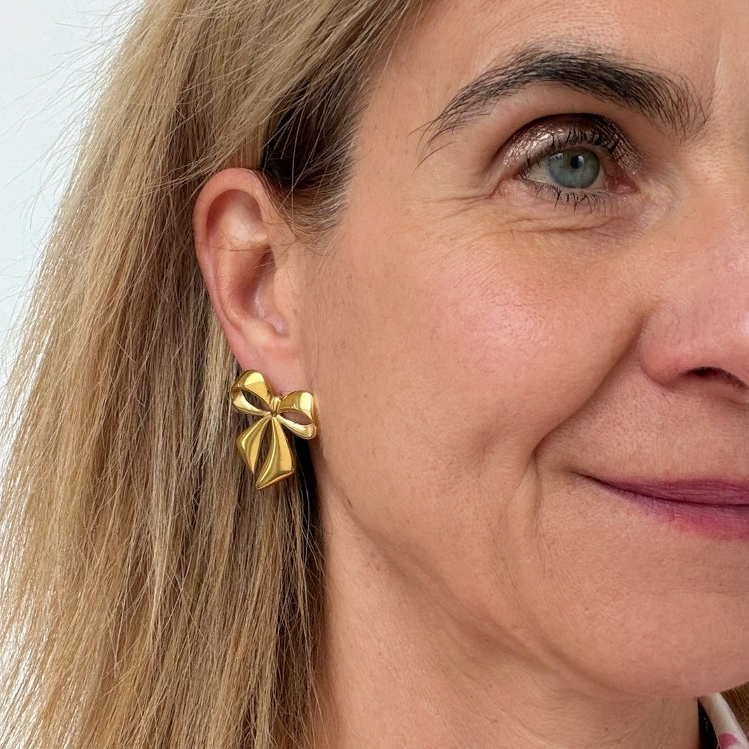 woman wearing gold bow shaped earrings