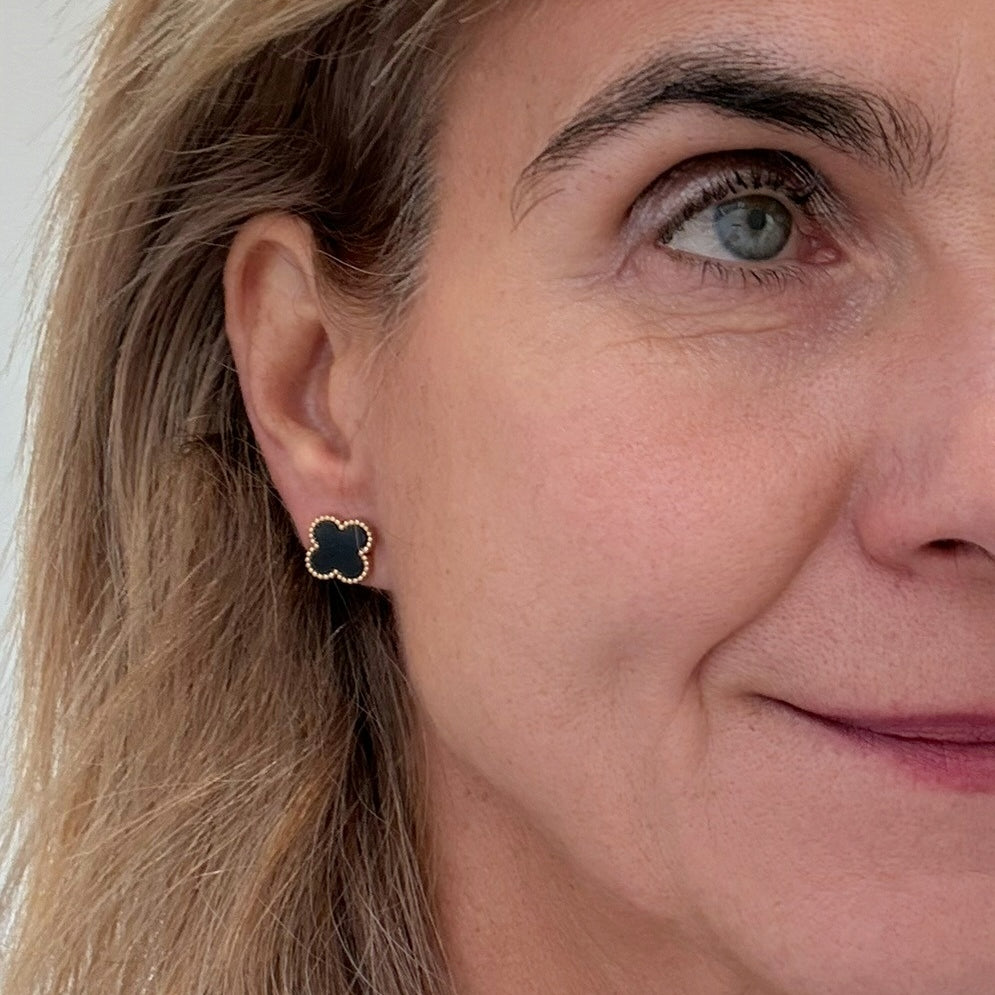 Close-up of a woman wearing a black clover-shaped earring.