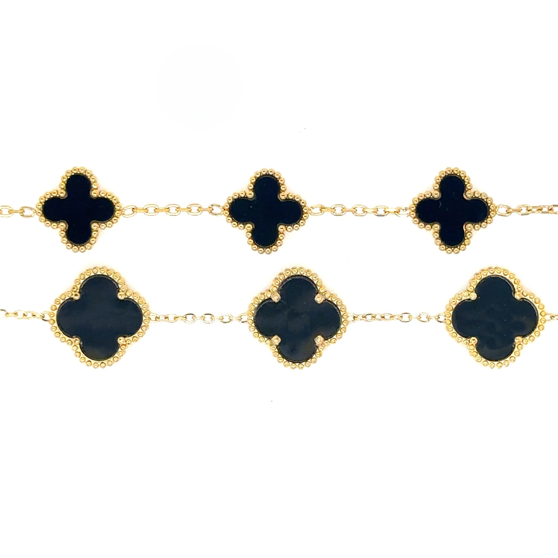 gold bracelet has five small and large clover charms in black enamel