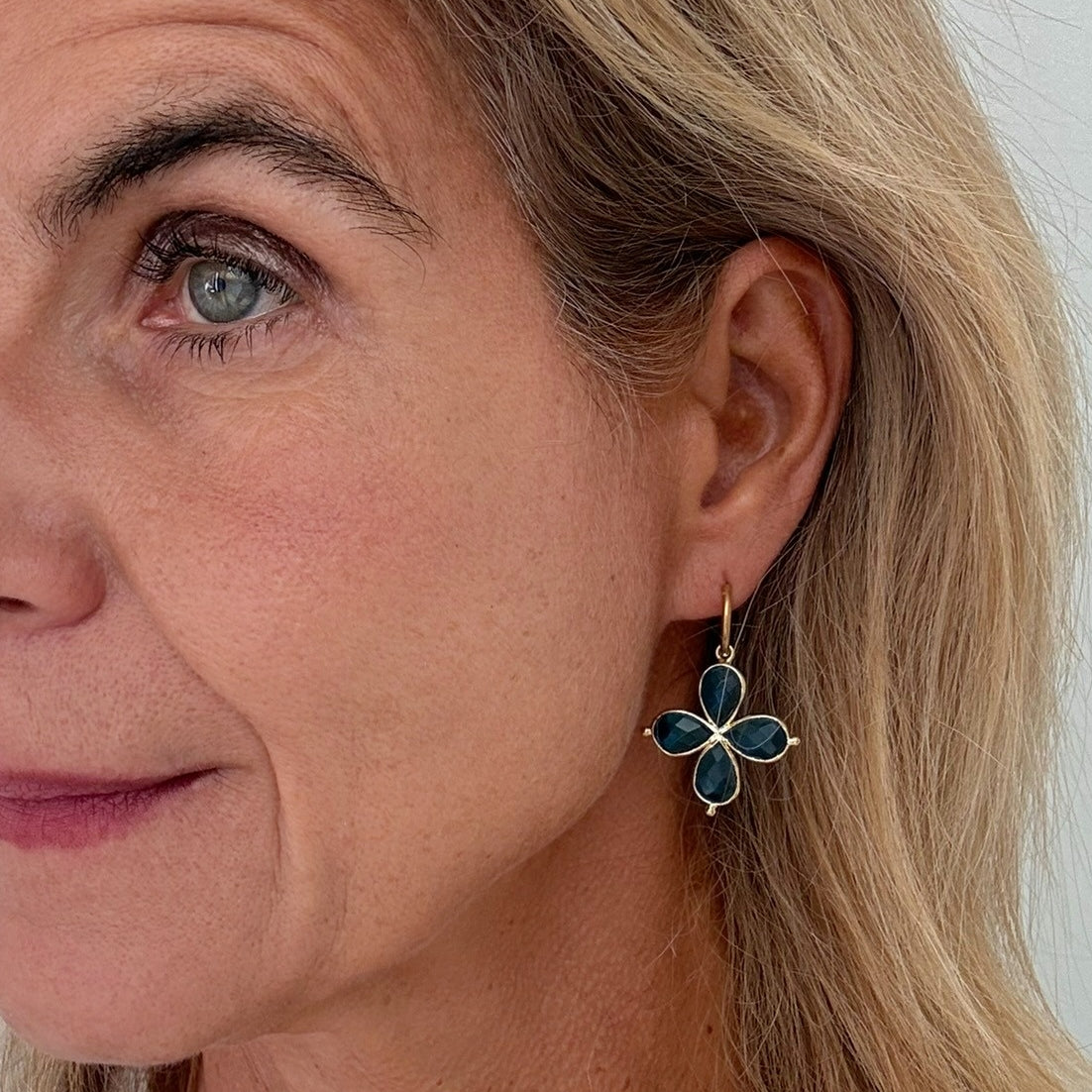Close-up of a woman wearing a blue flower-shaped earring.