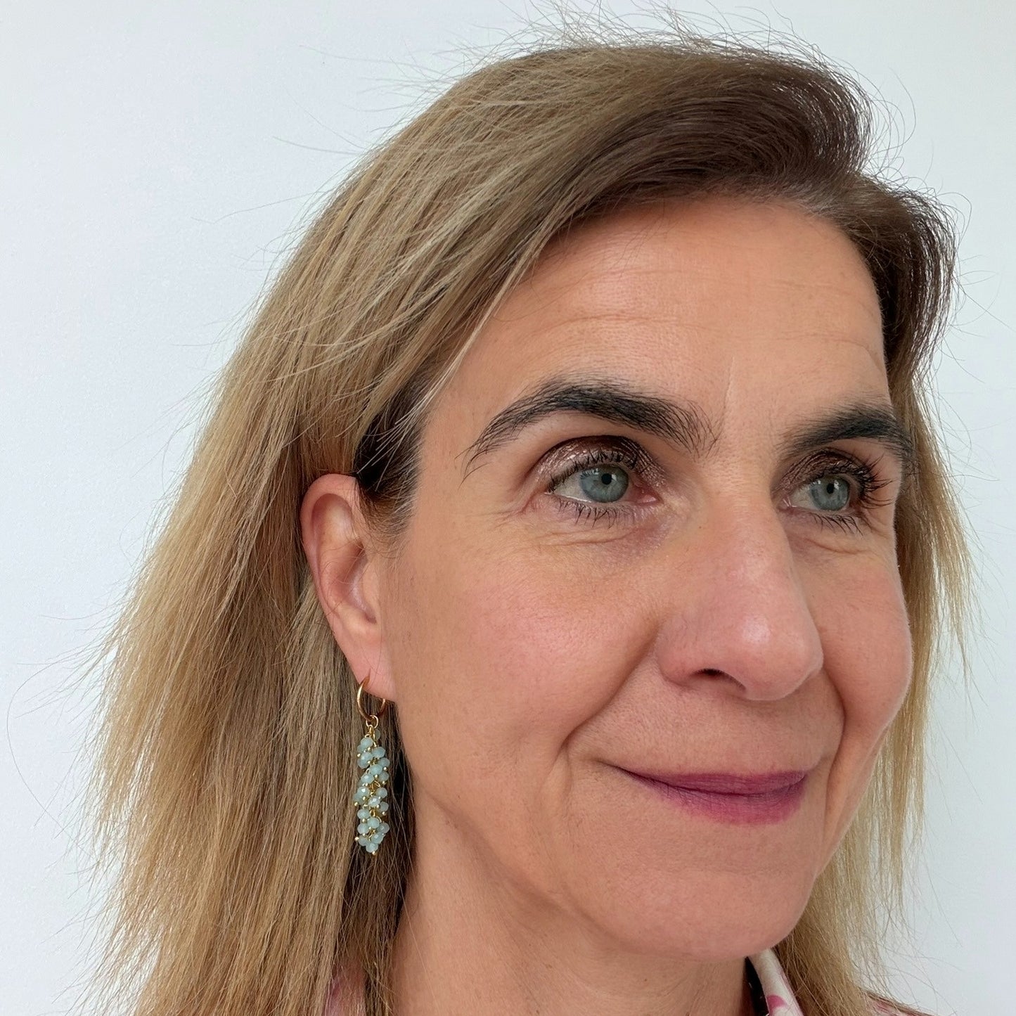 woman wearing gold hoop earrings with  dangling blue gemstone beads