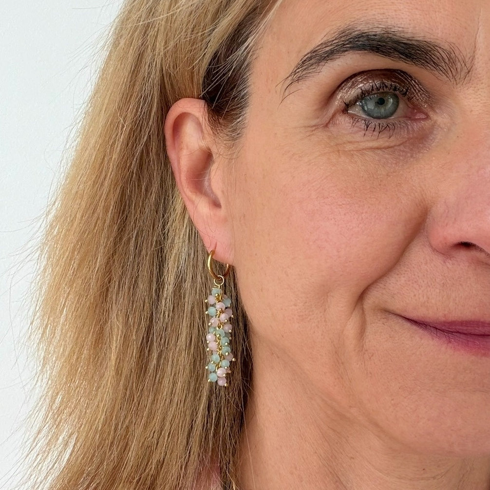 woman wearing gold hoop earrings with  dangling pink and blue beads