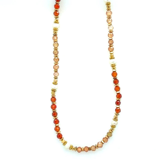A beaded necklace featuring faceted orange-red agate beads, light peach and cream beads, and small gold spacer beads, displayed against a plain white background.