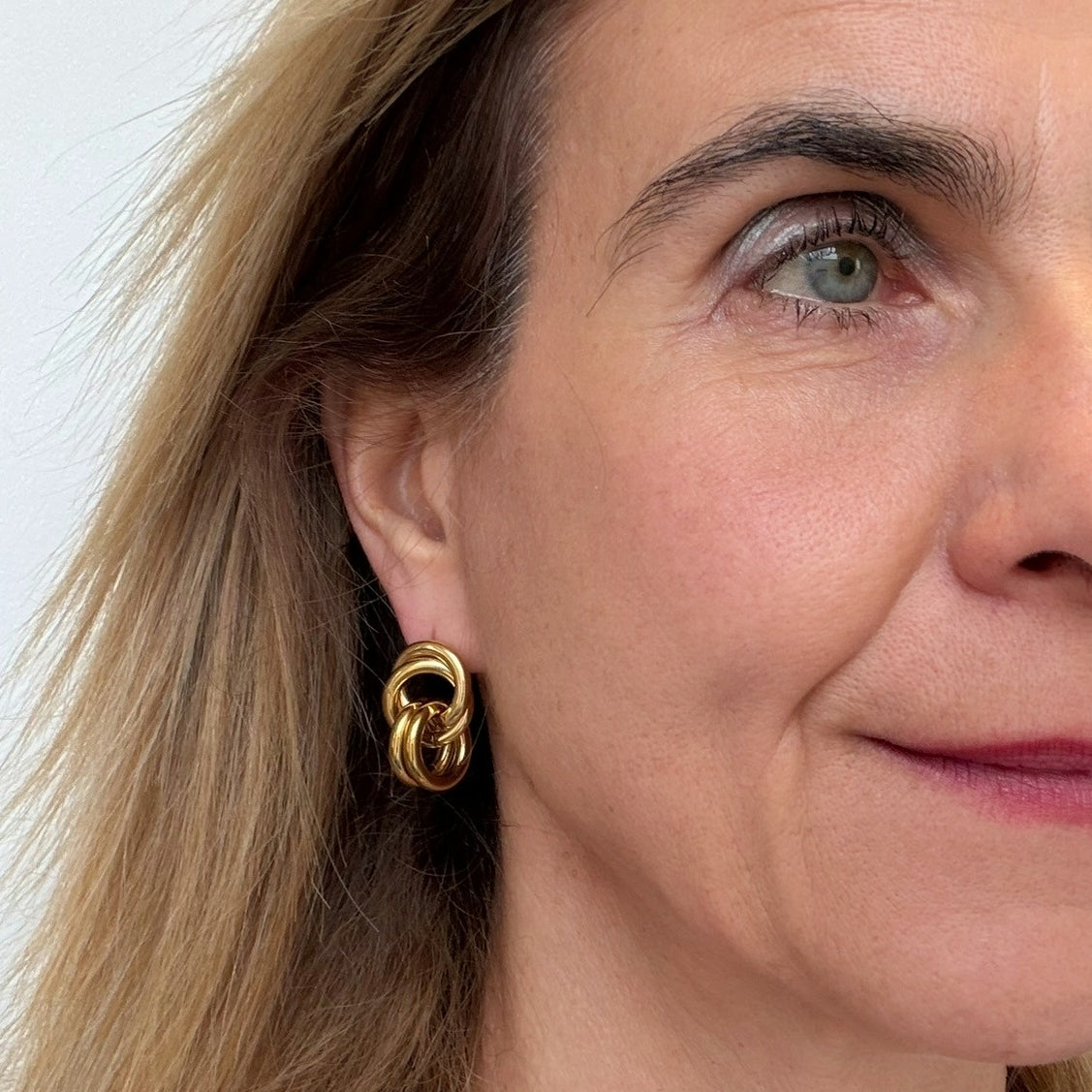 woman wearring gold earrings with intertwining circles.
