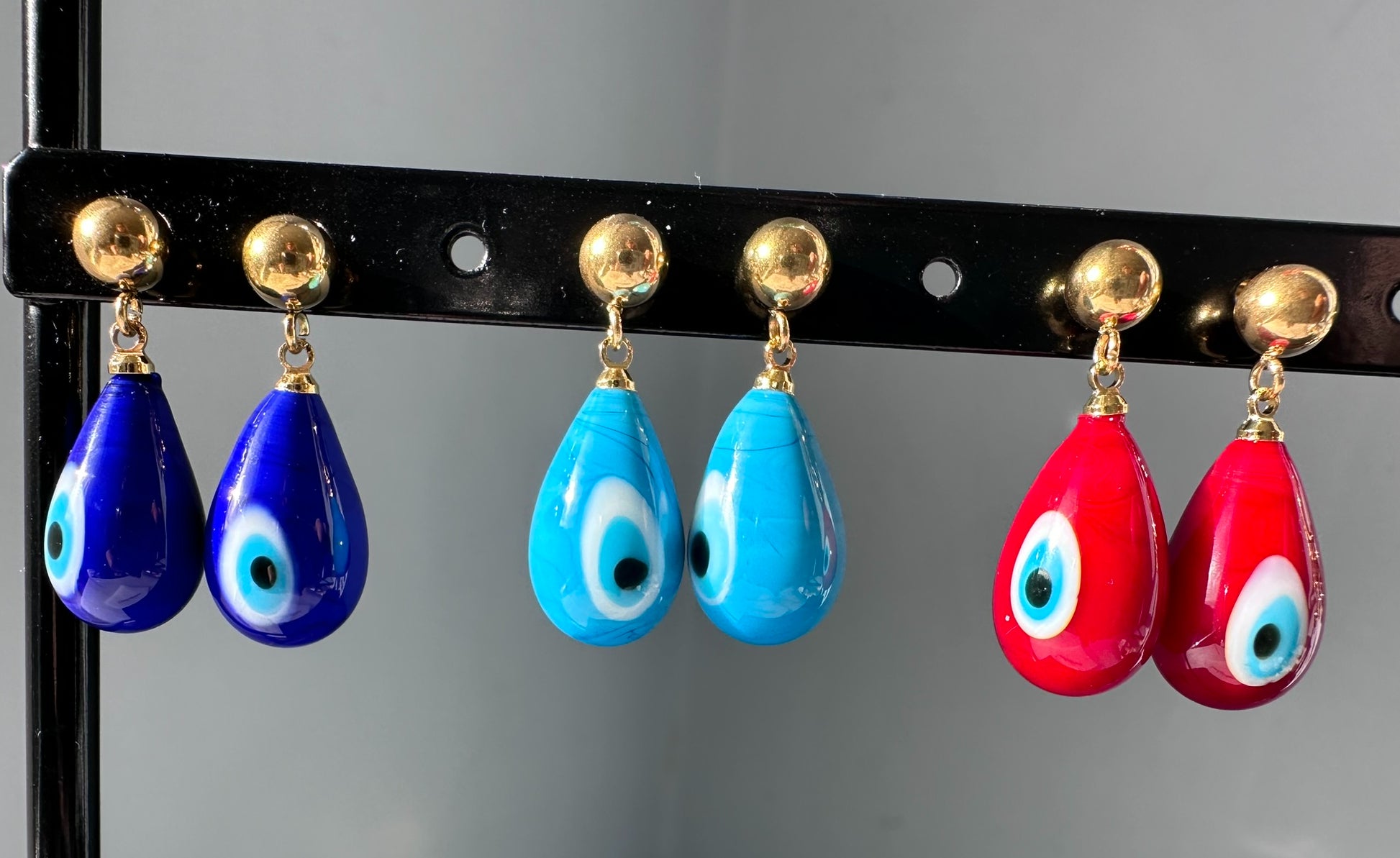 Gold stud earrings with evil eye glass charms in blue and red