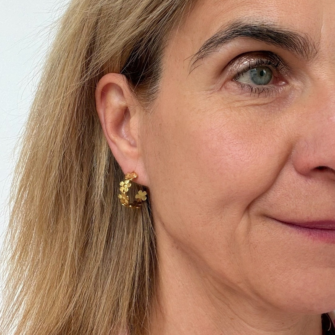 woman wearing gold hoop earrings with flowers all around