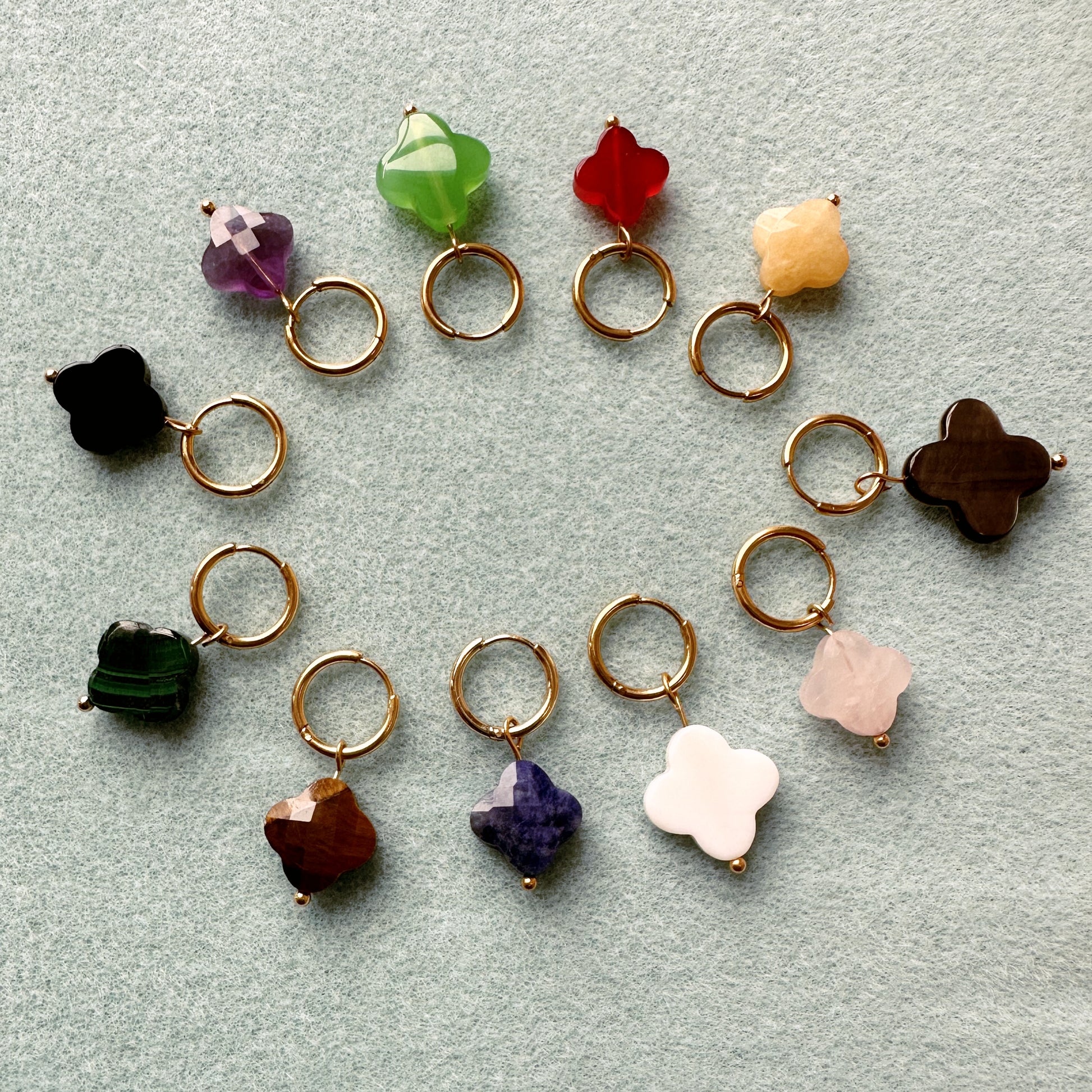 gold hoop earrings with clover shaped charms made of rainbow of faceted semi-precious gemstones