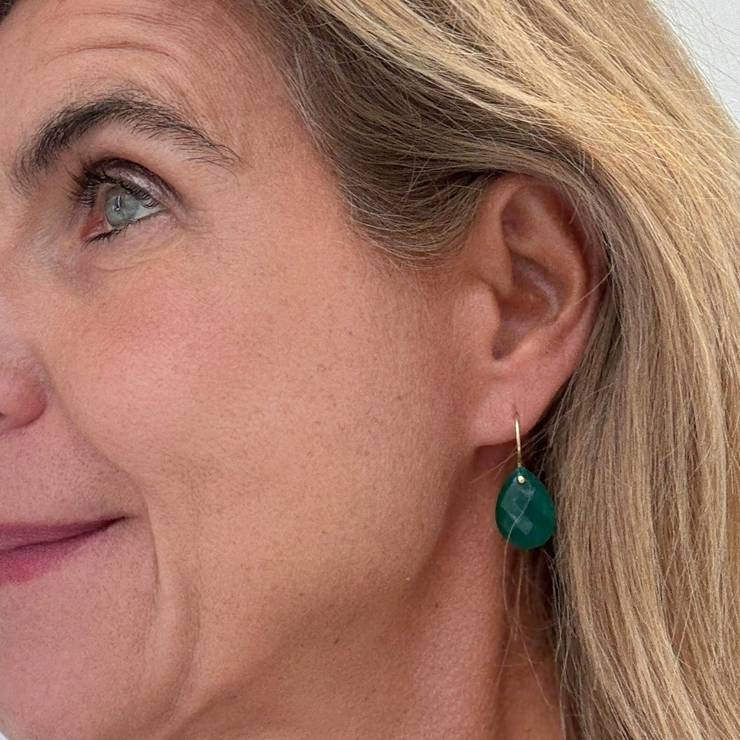 Close-up of a woman wearing a green agate teardrop earring.